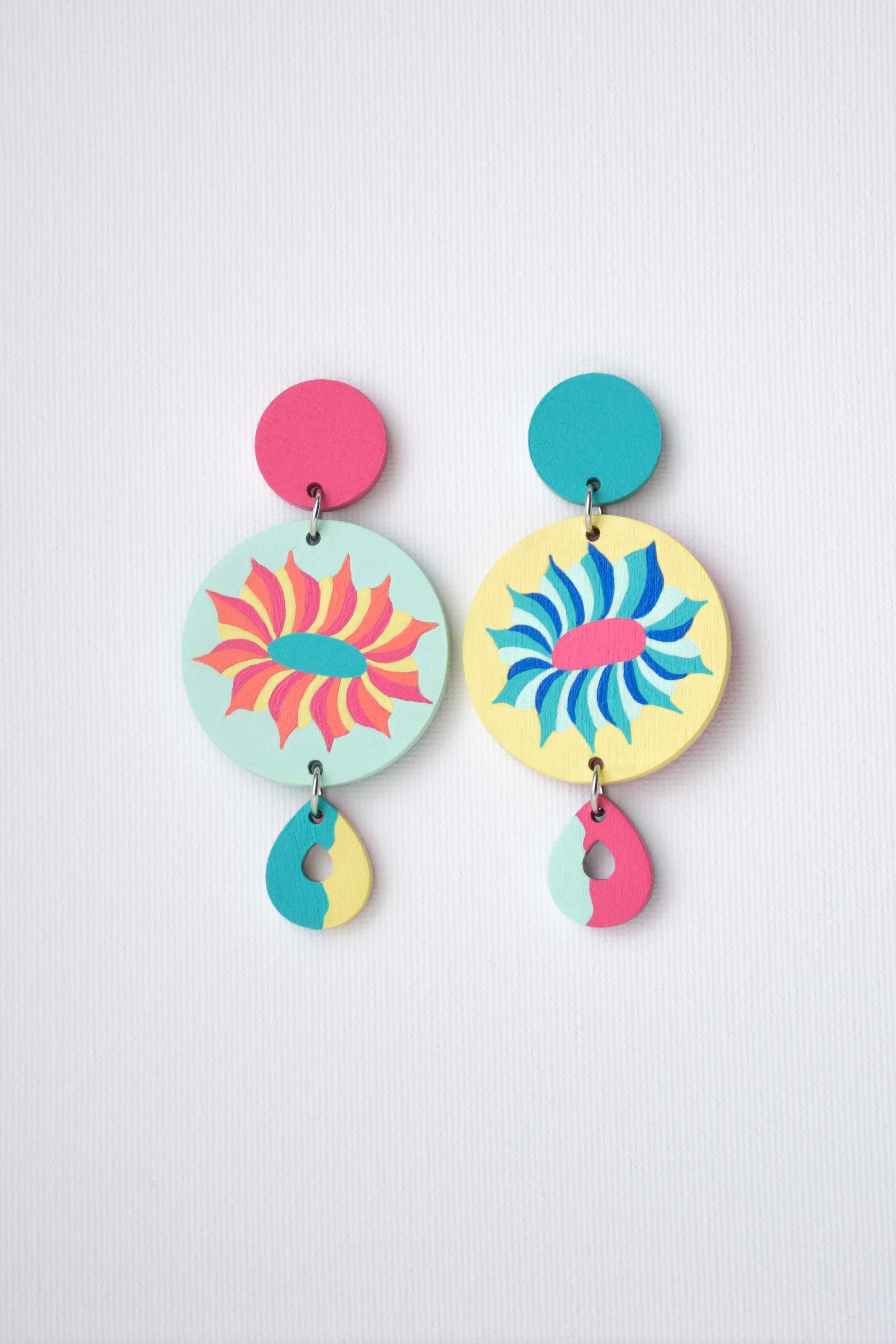 Colorful earrings with floral designs on a light gray background