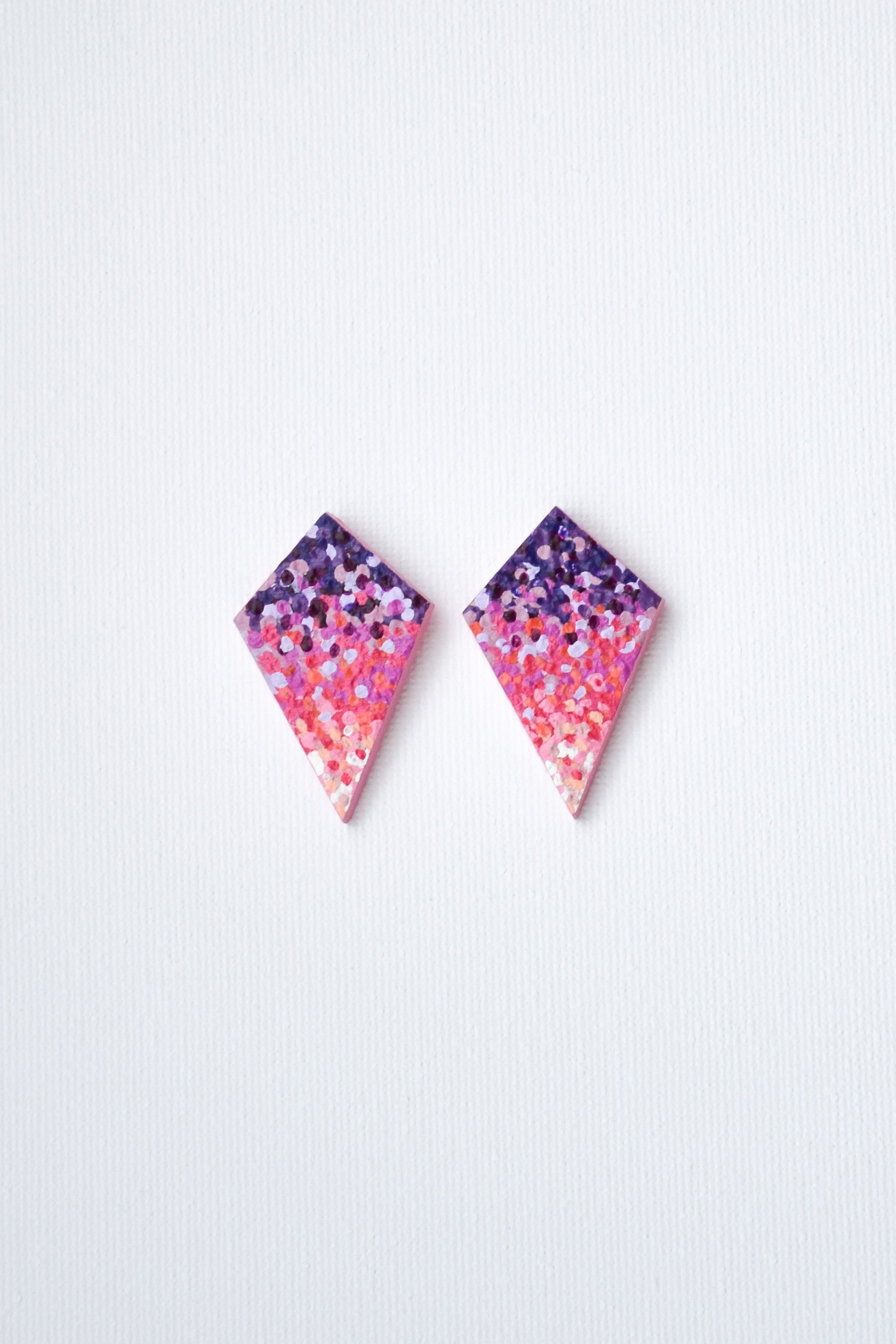 Pair of geometric earrings with pink and purple gradient on a white background