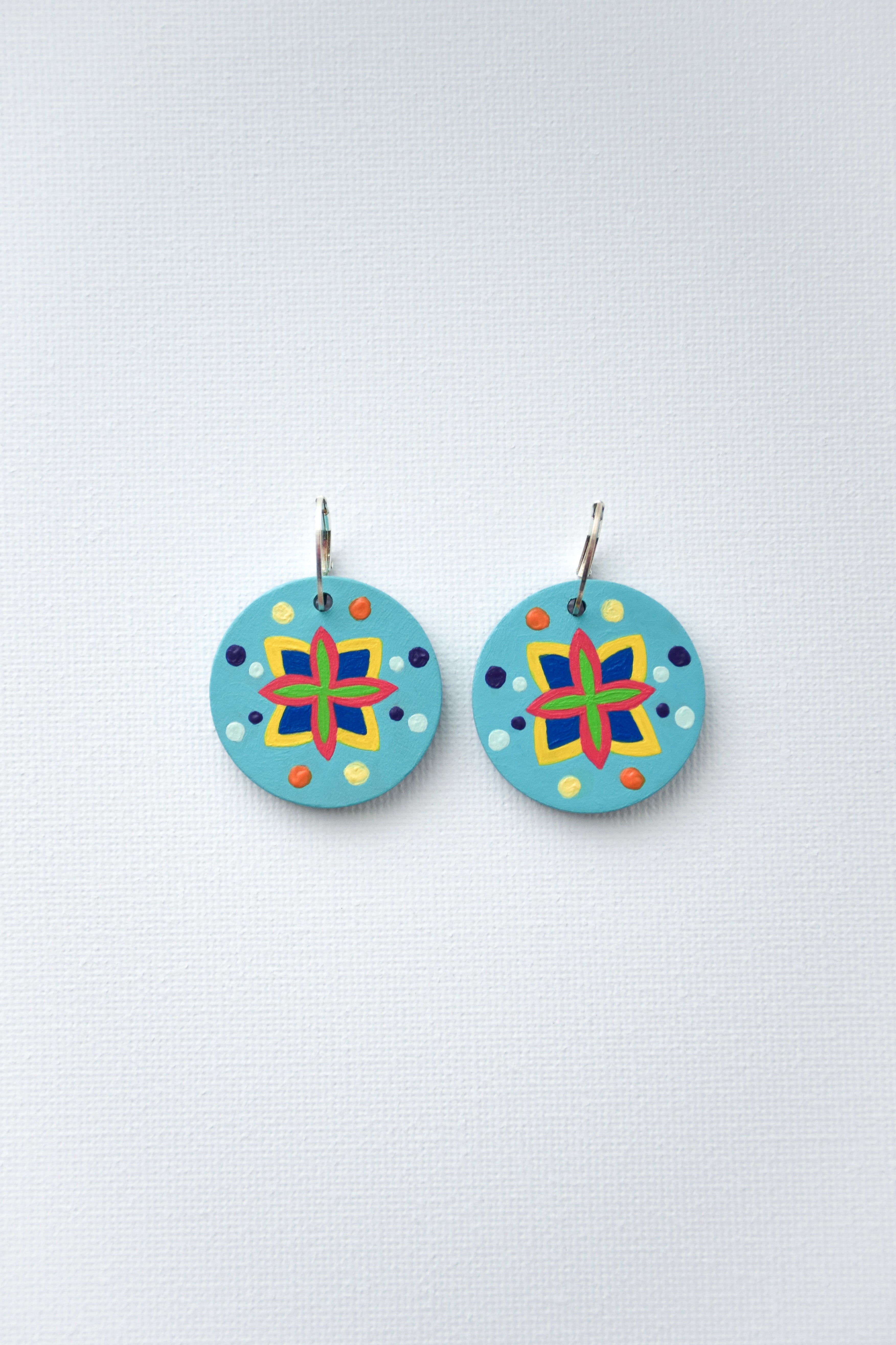 Pair of colorful circular earrings with sterling silver hoops on a light gray background