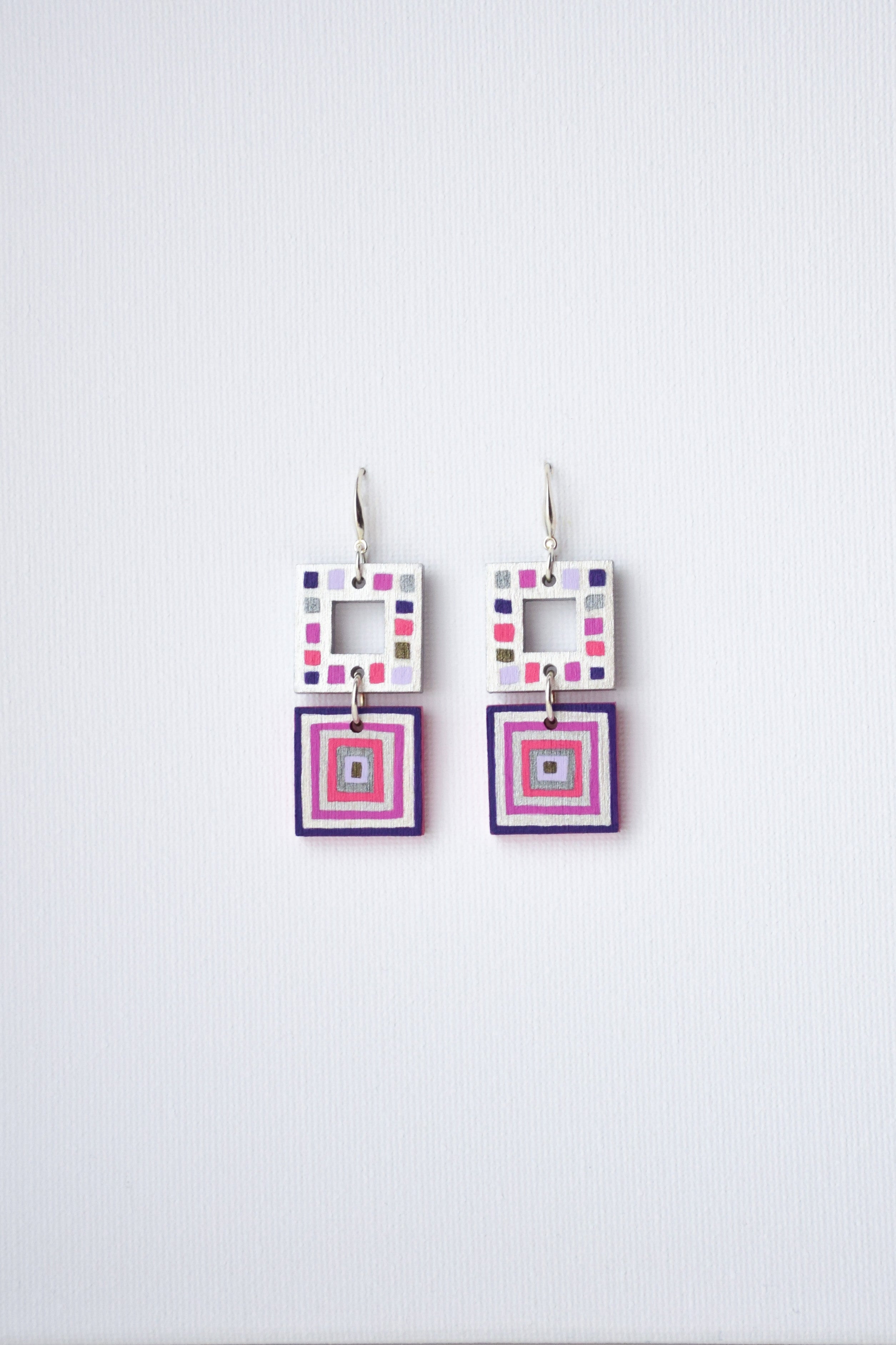 Pair of square-shaped earrings with colorful patterns on a white background