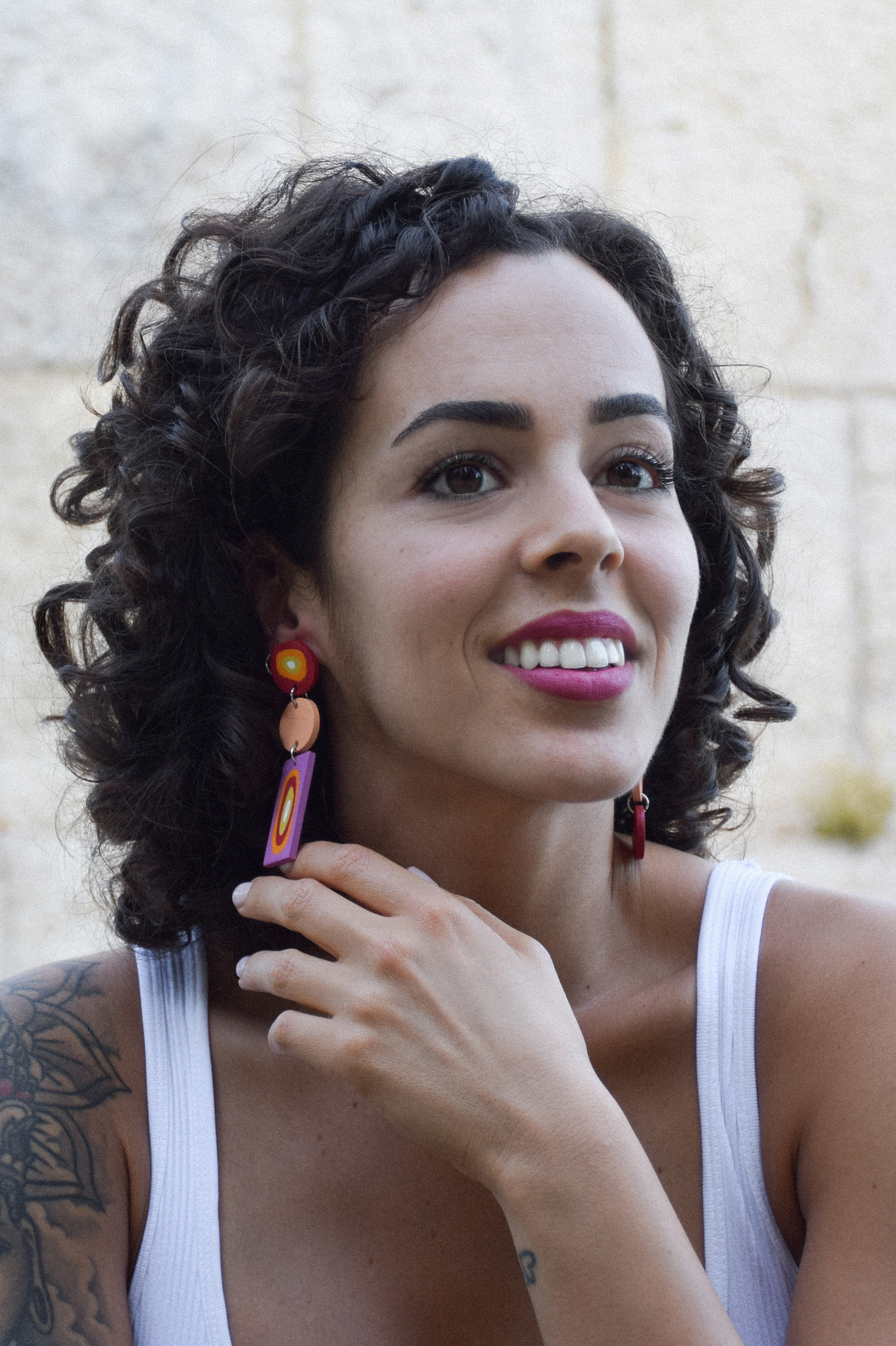 Woman with curly hair wearing colorful earrings outdoors