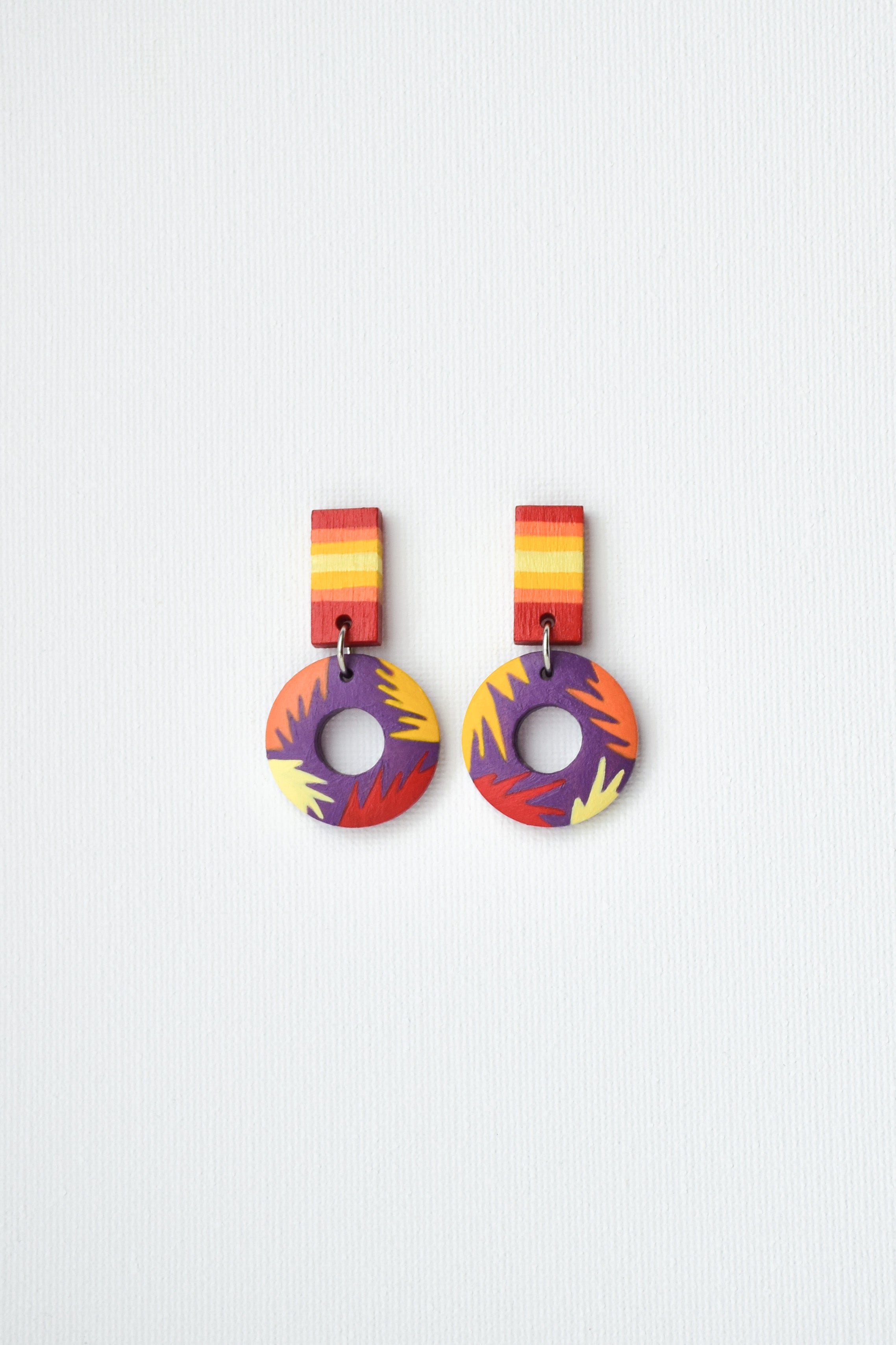 Colorful hand-painted earrings with circular designs on a light gray background