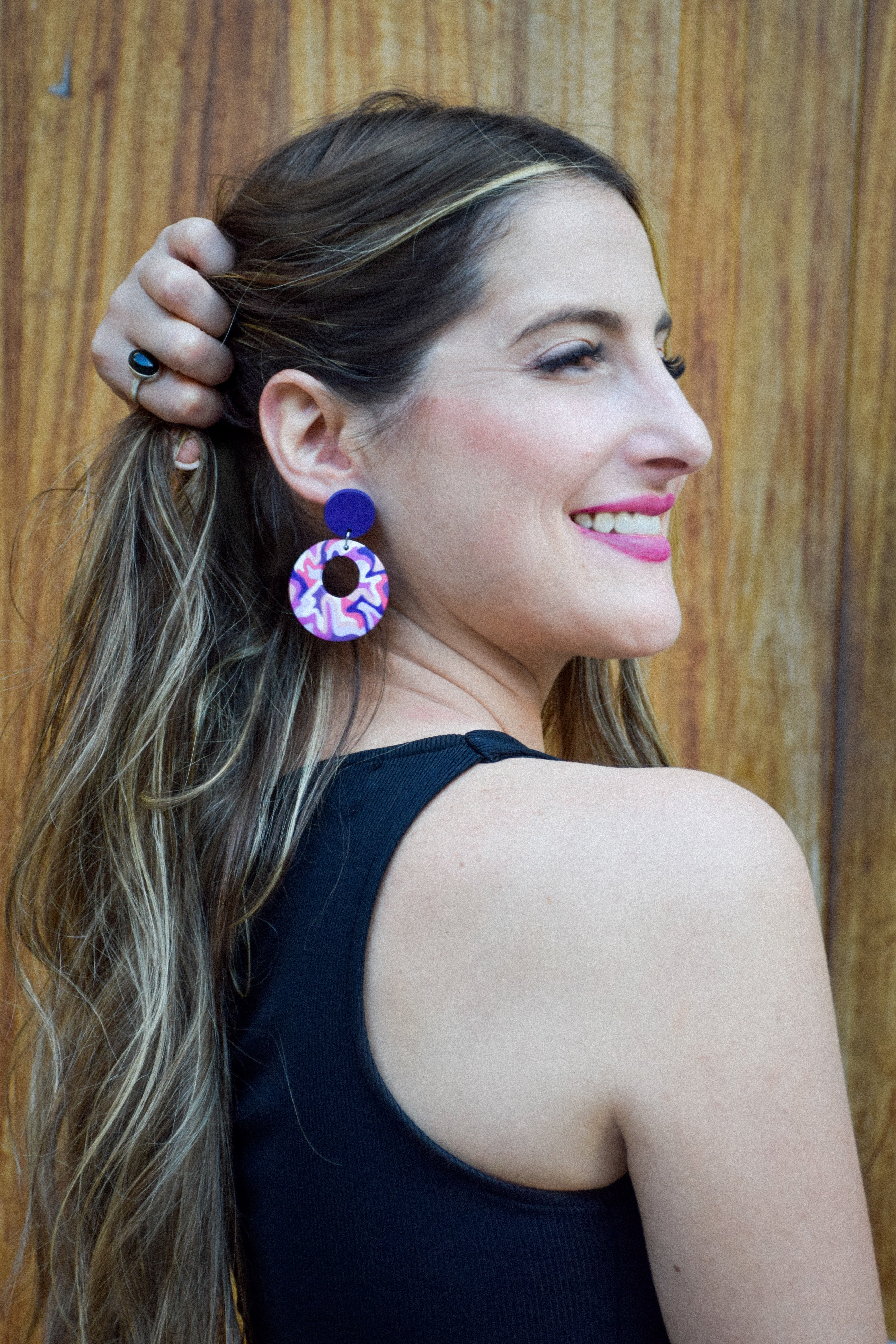 Woman wearing colorful earrings with a wooden background