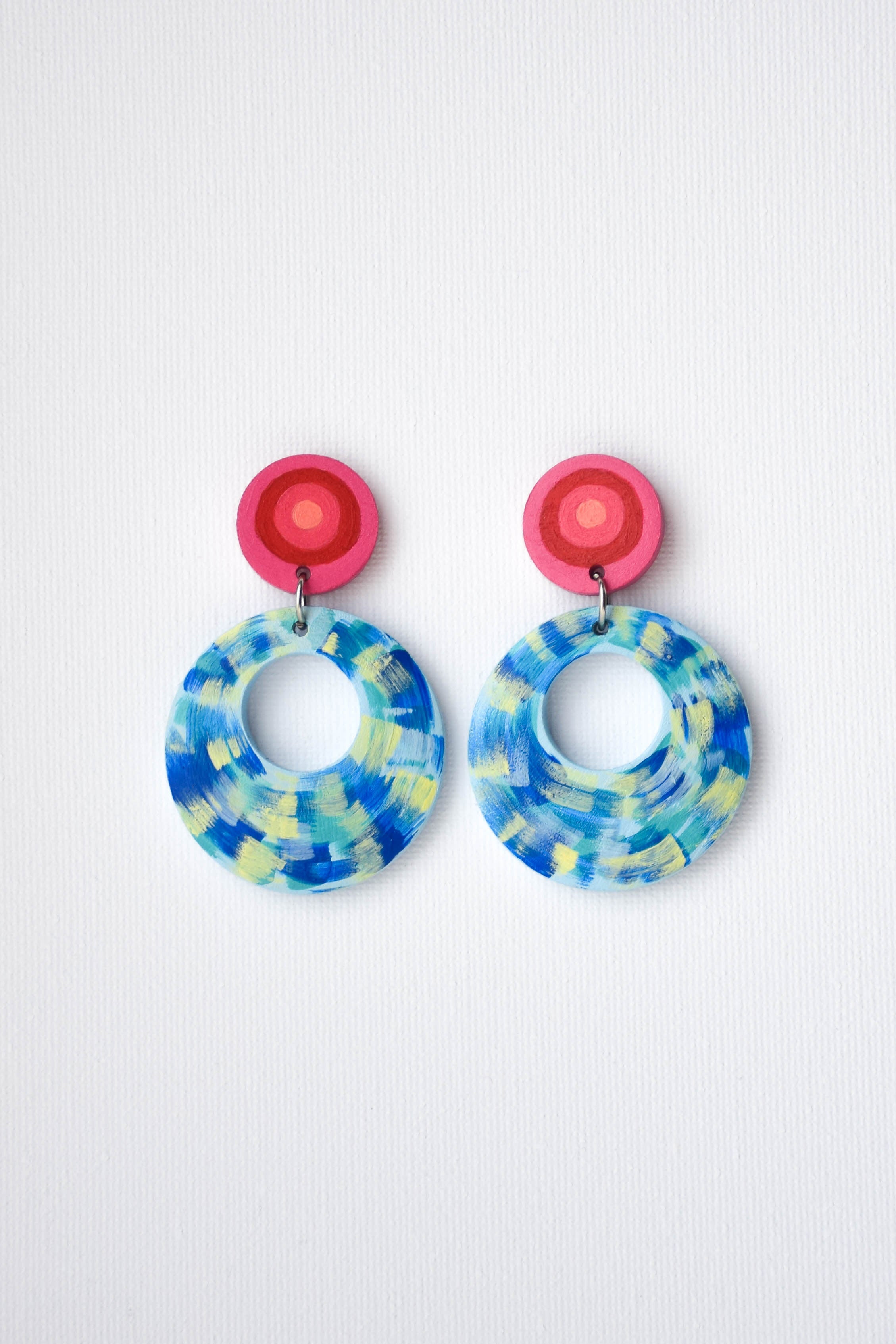 Colorful circular earrings with pink tops on a white background