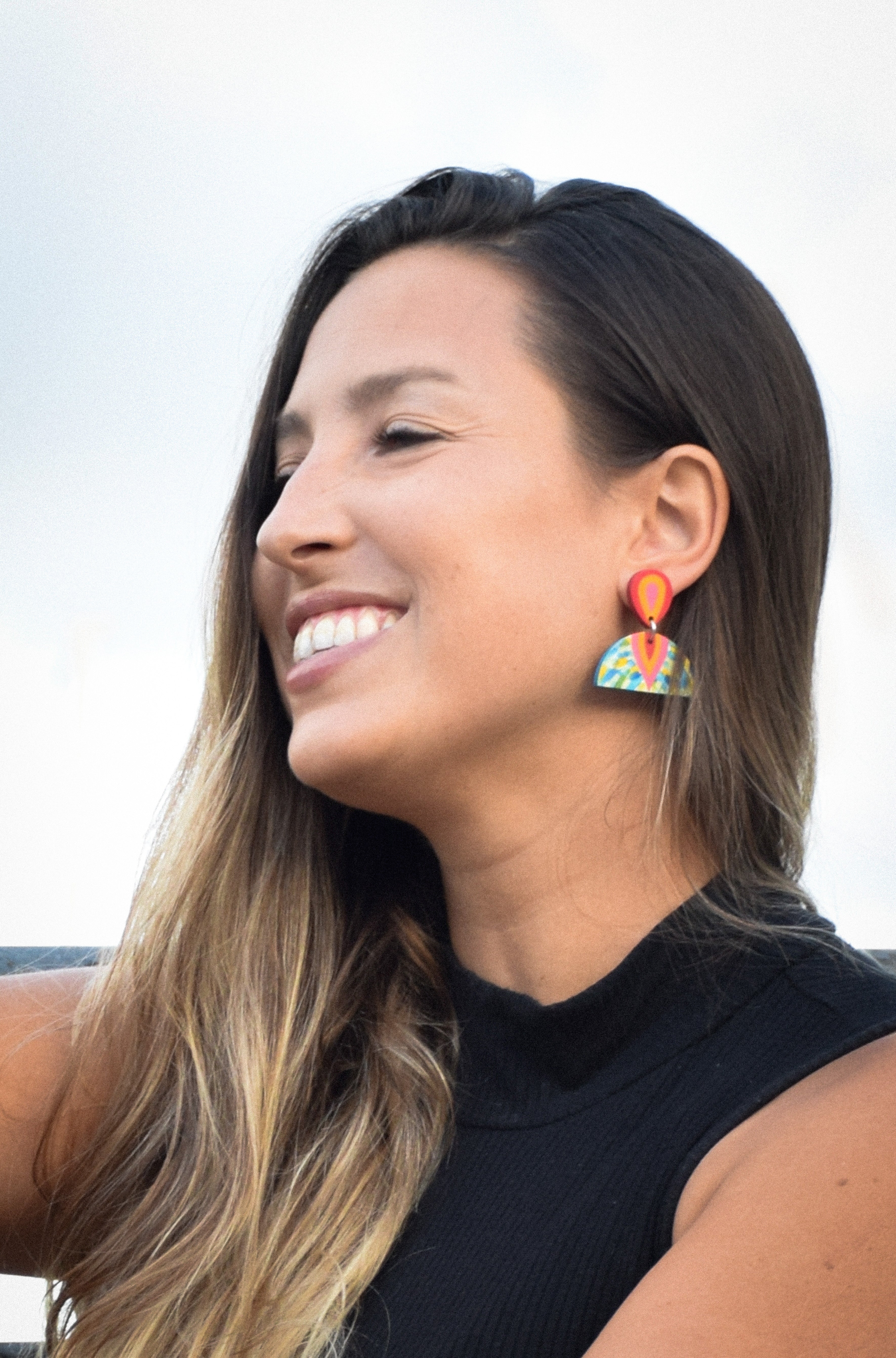 Woman wearing colorful earrings with a blurred background