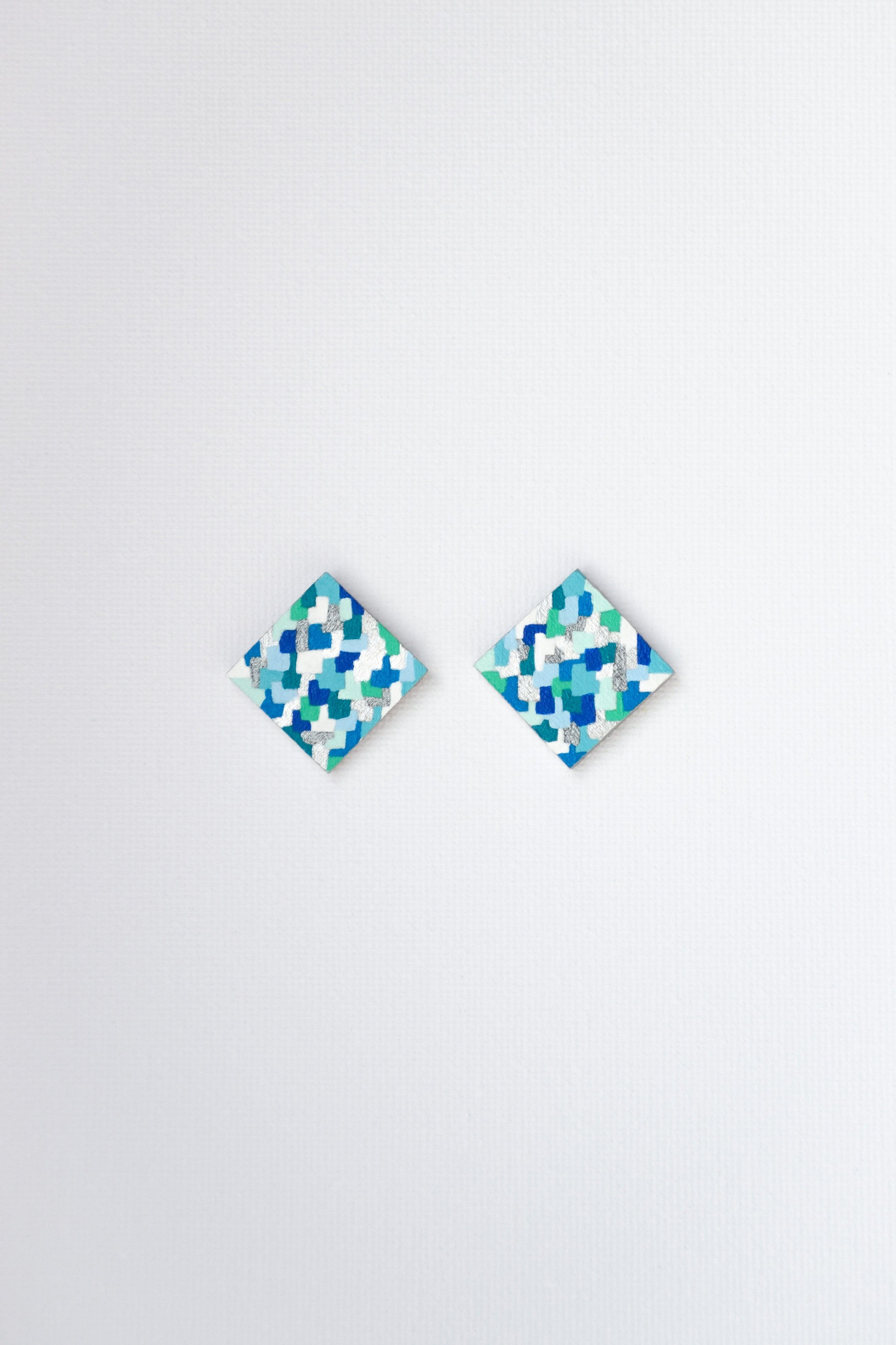 Pair of square blue and green patterned earrings on a white background