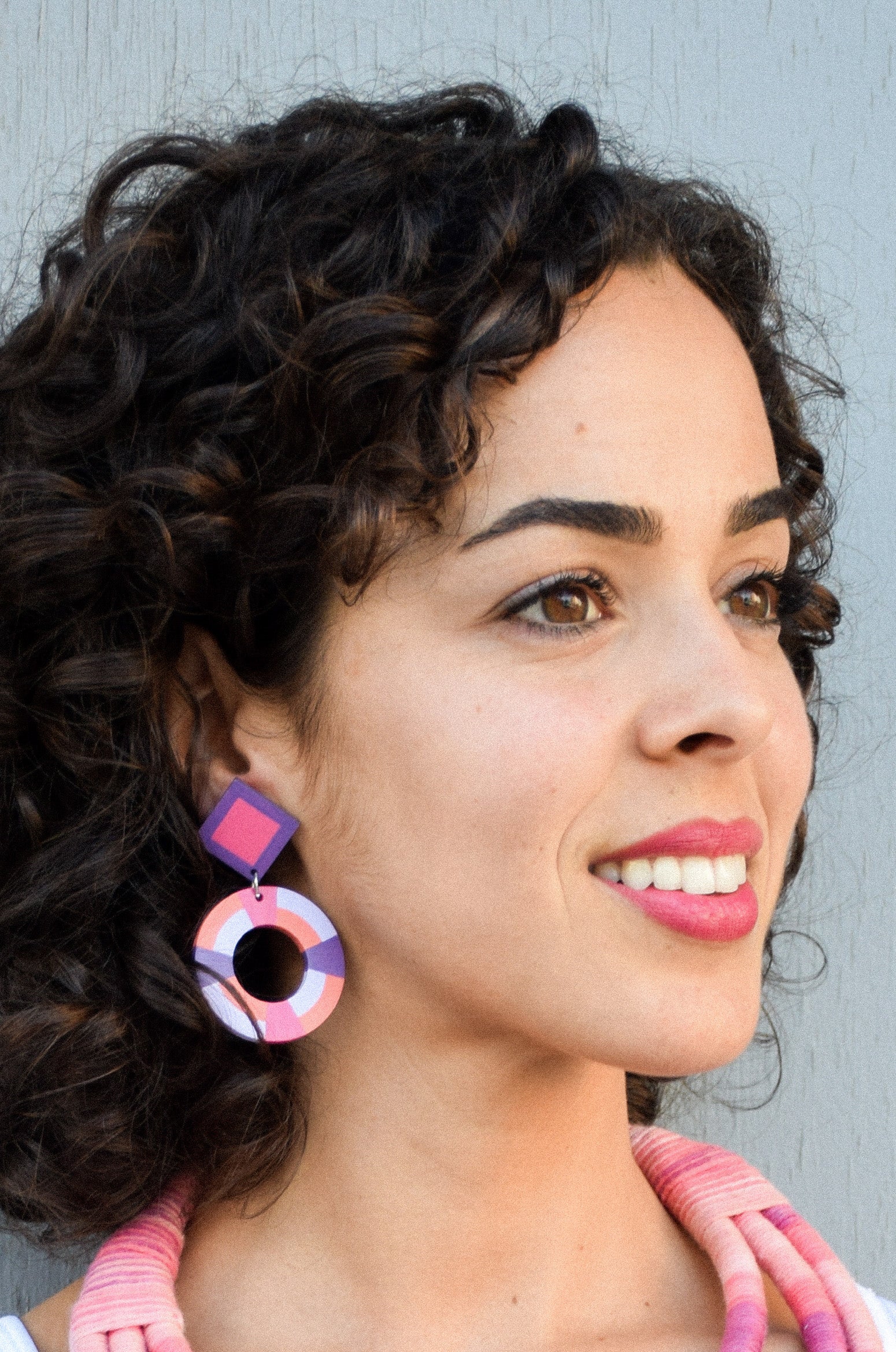 Woman wearing colorful earrings with a neutral background
