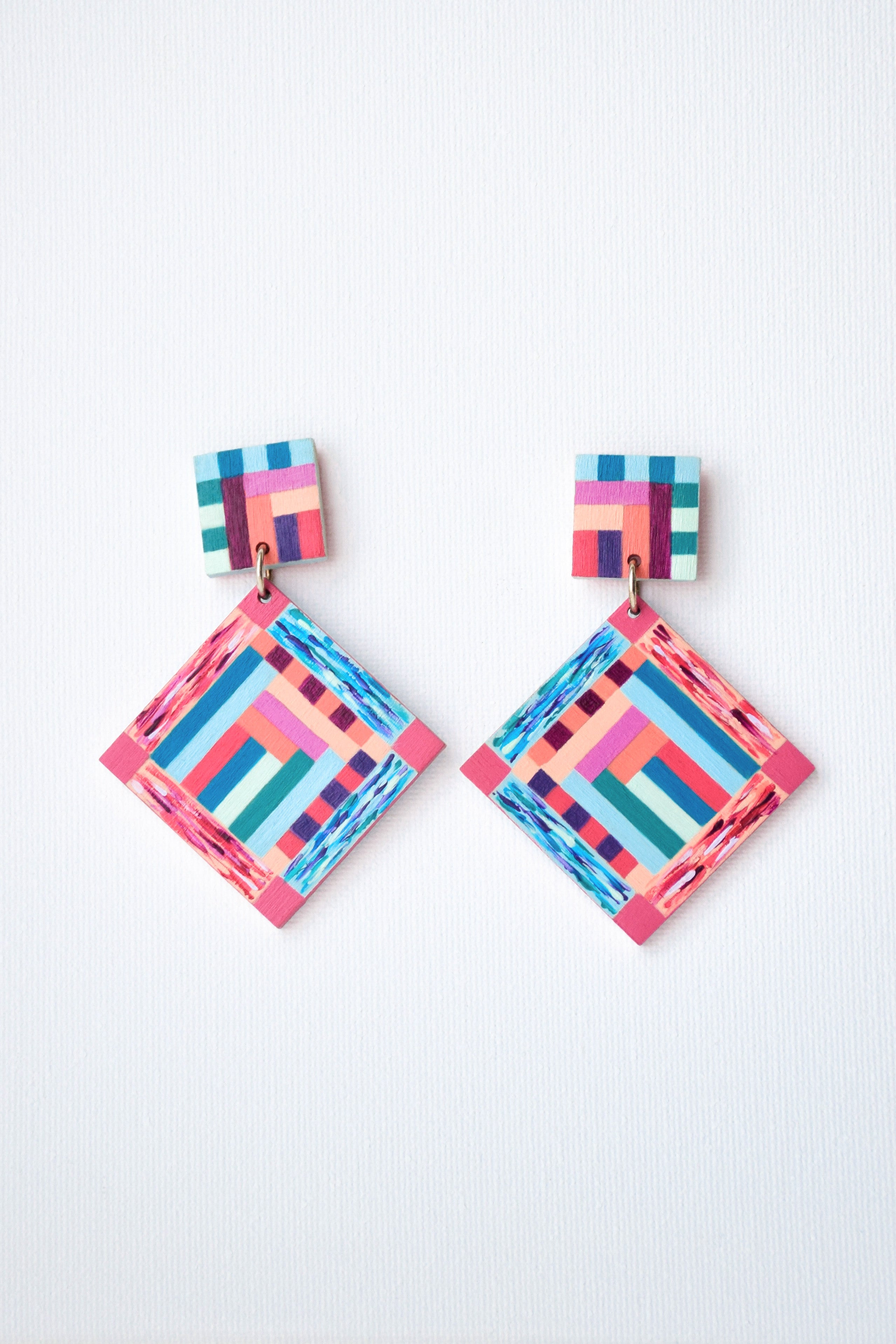 Colorful hand-painted geometric patterned earrings on a light gray background