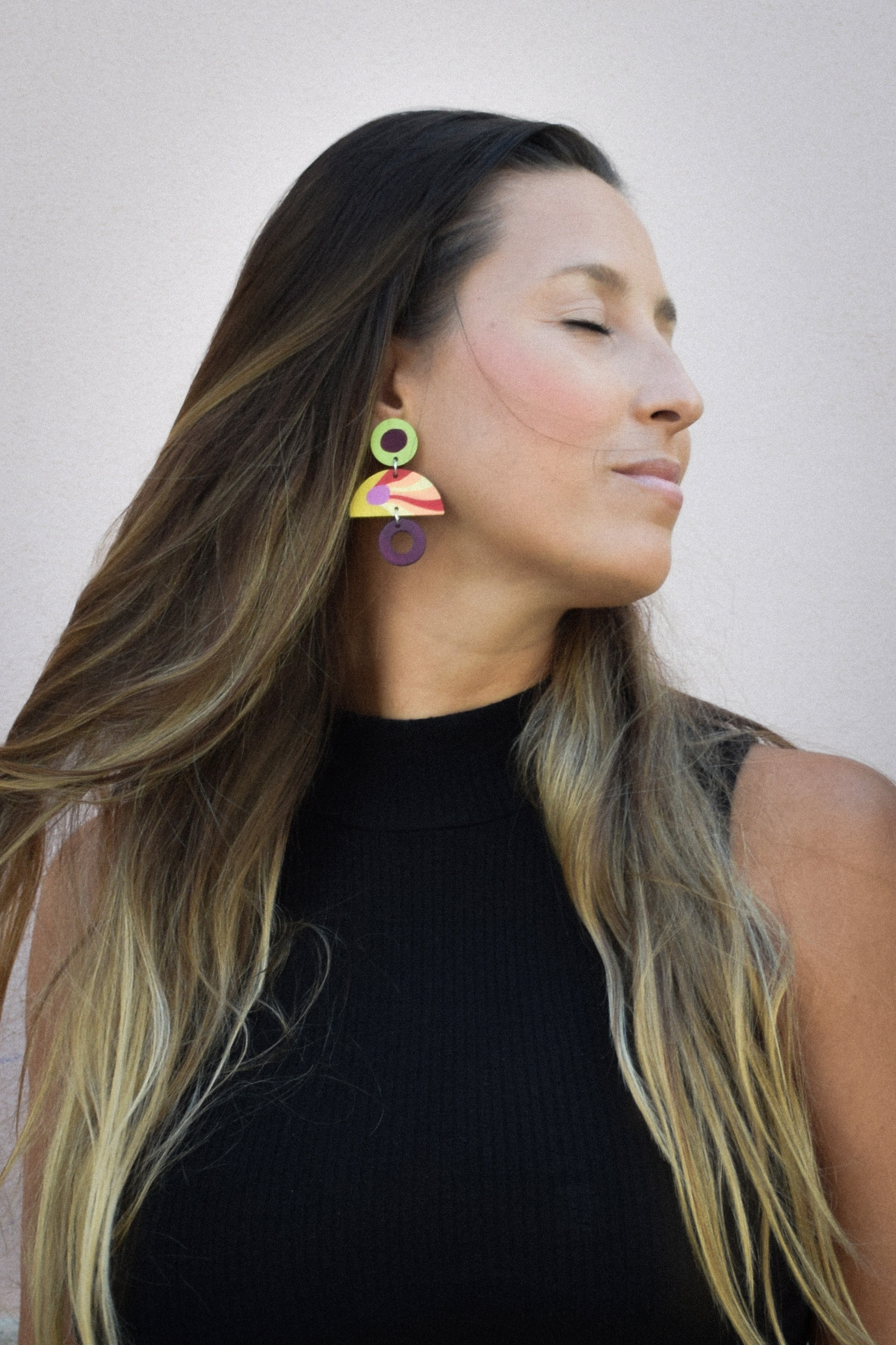 Woman wearing colorful earrings with a plain background