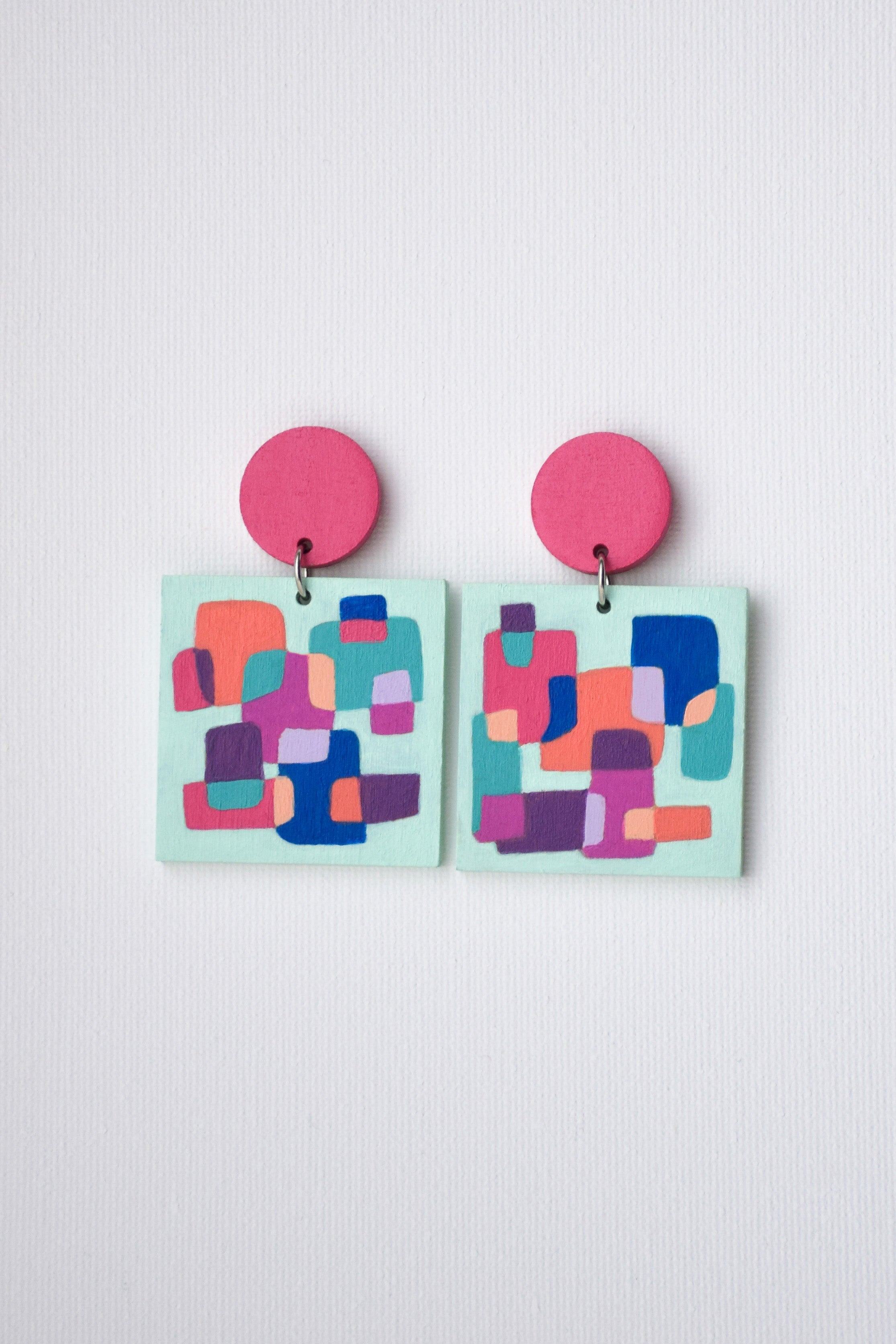 Colorful geometric earrings with pink tops on a light gray background