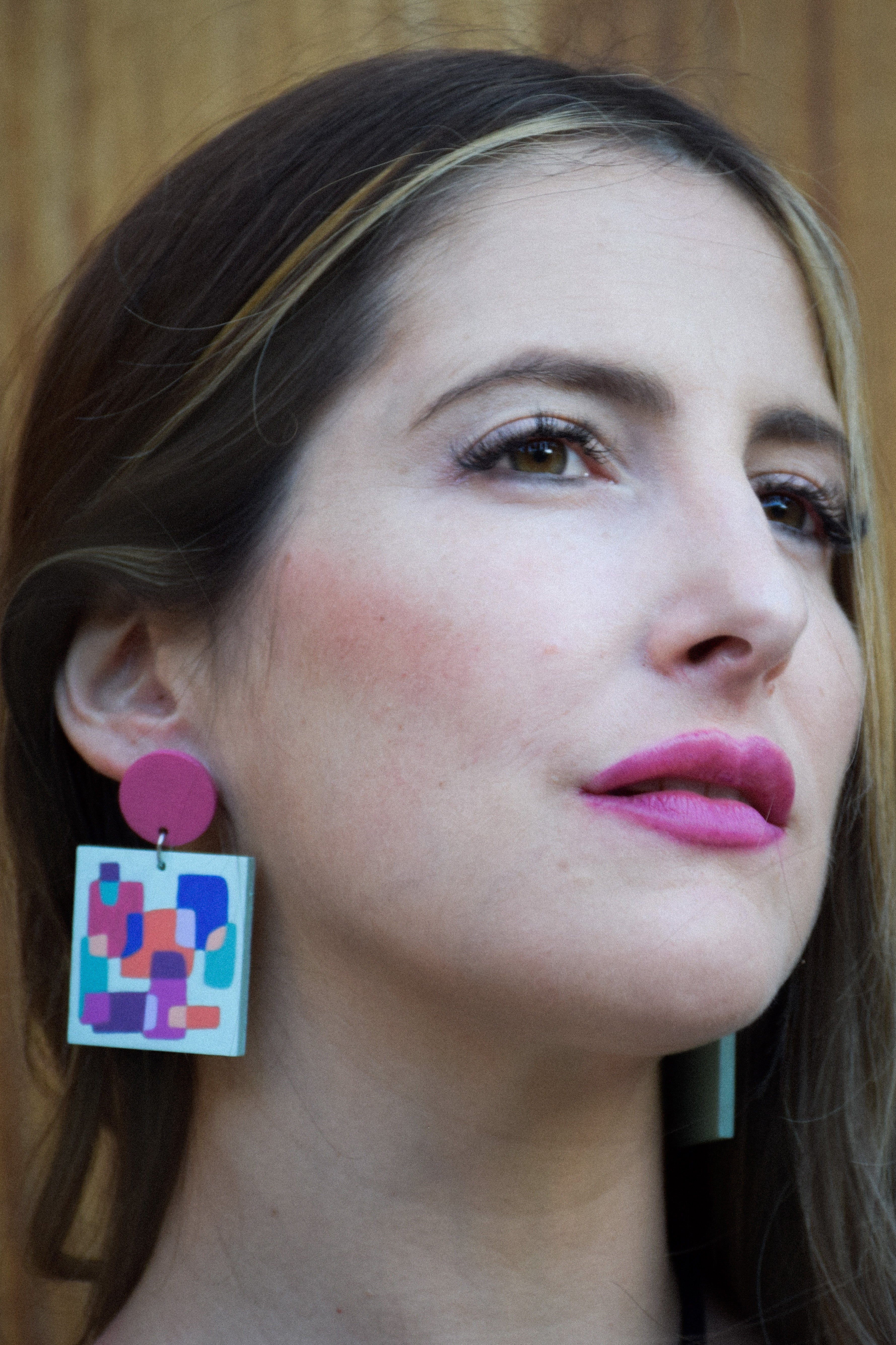 Close-up of a woman wearing colorful geometric earrings with a blurred background