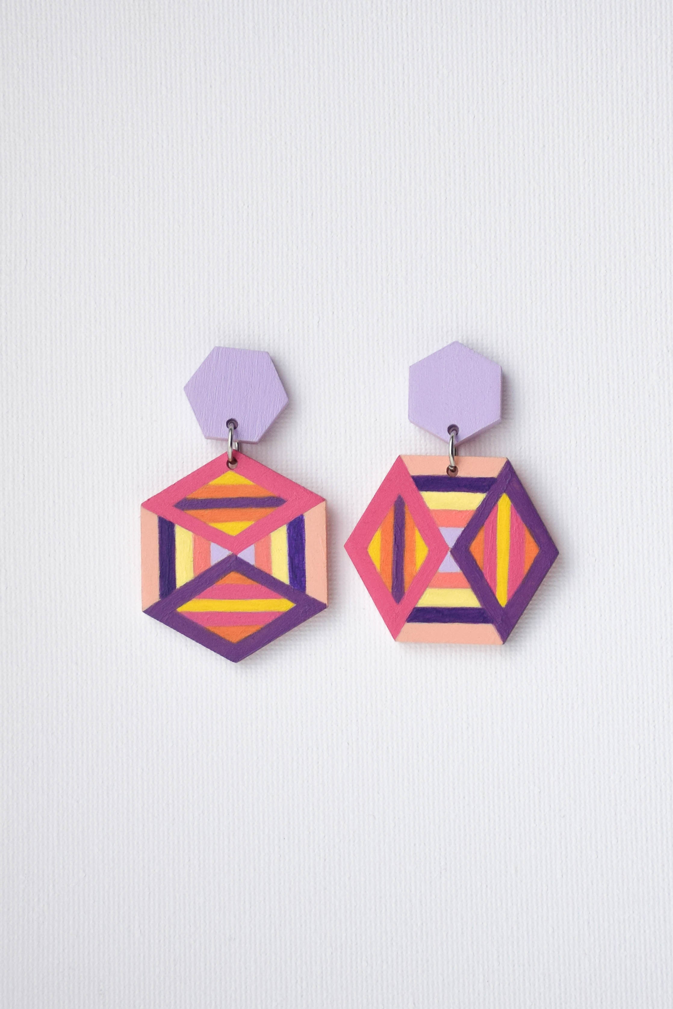 Geometric earrings with colorful design on a light purple background