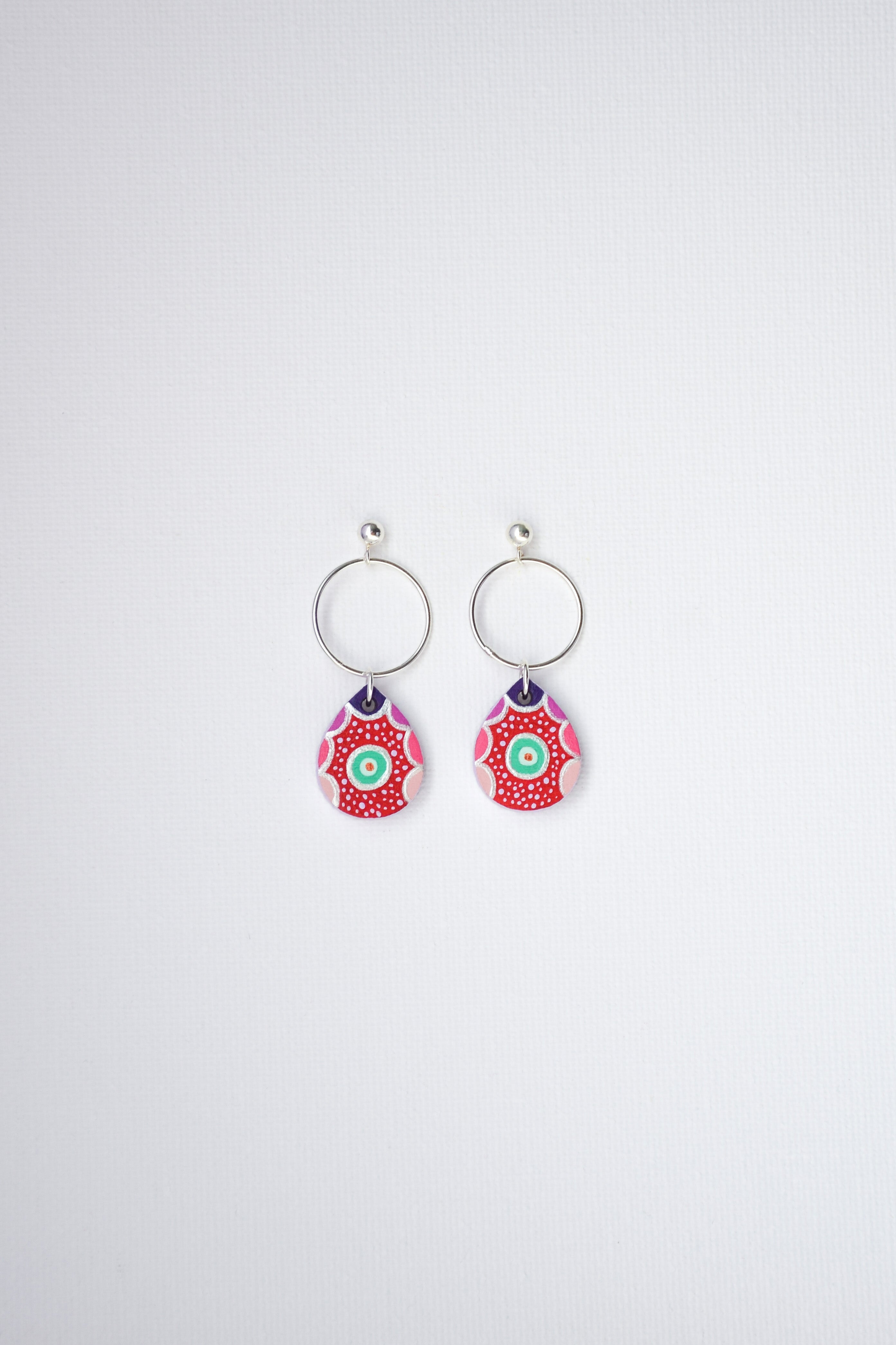 Pair of hand-painted earrings with colorful designs and sterling silver hoops on a white background