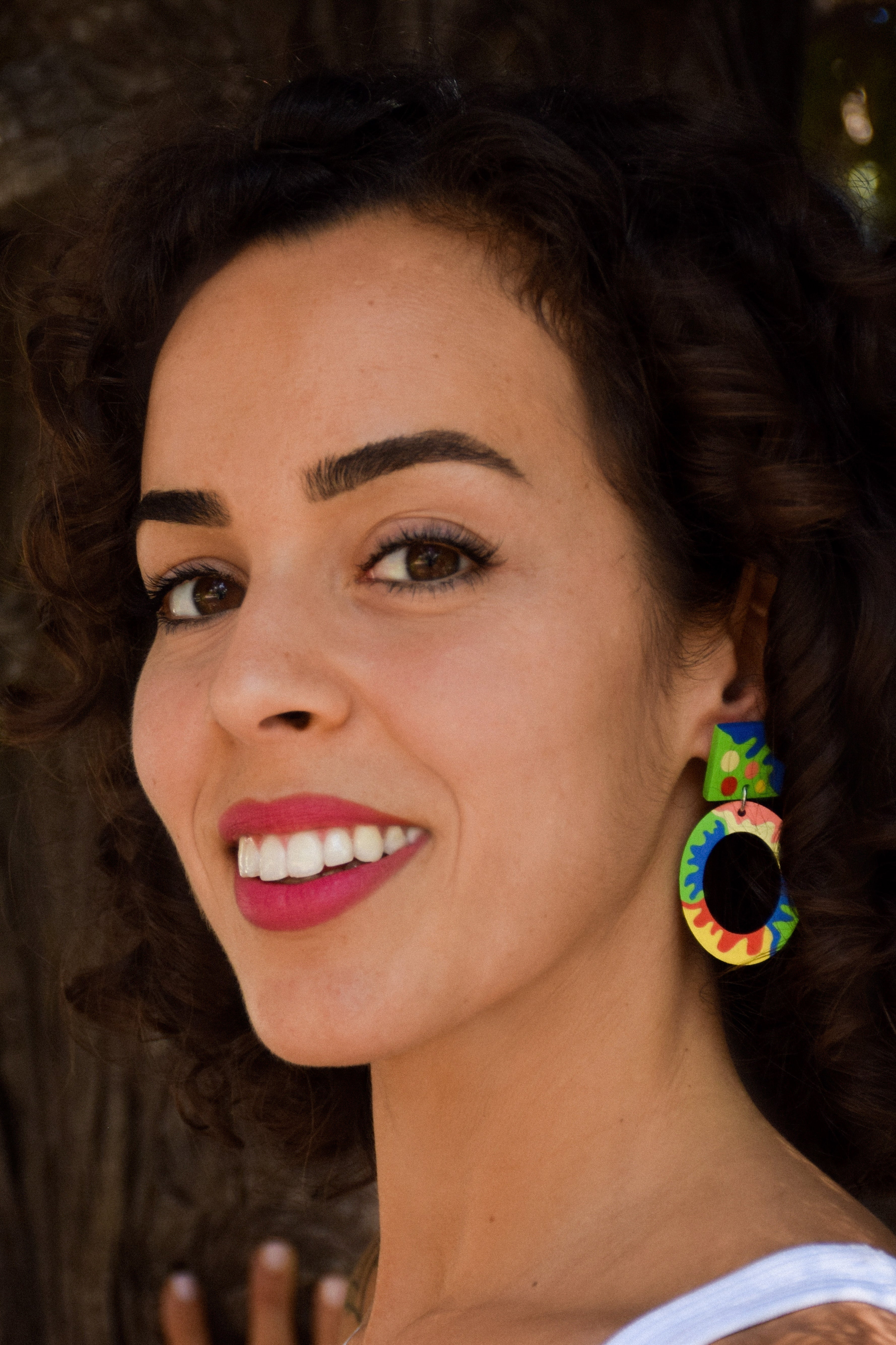 Woman wearing colorful earrings with a blurred background