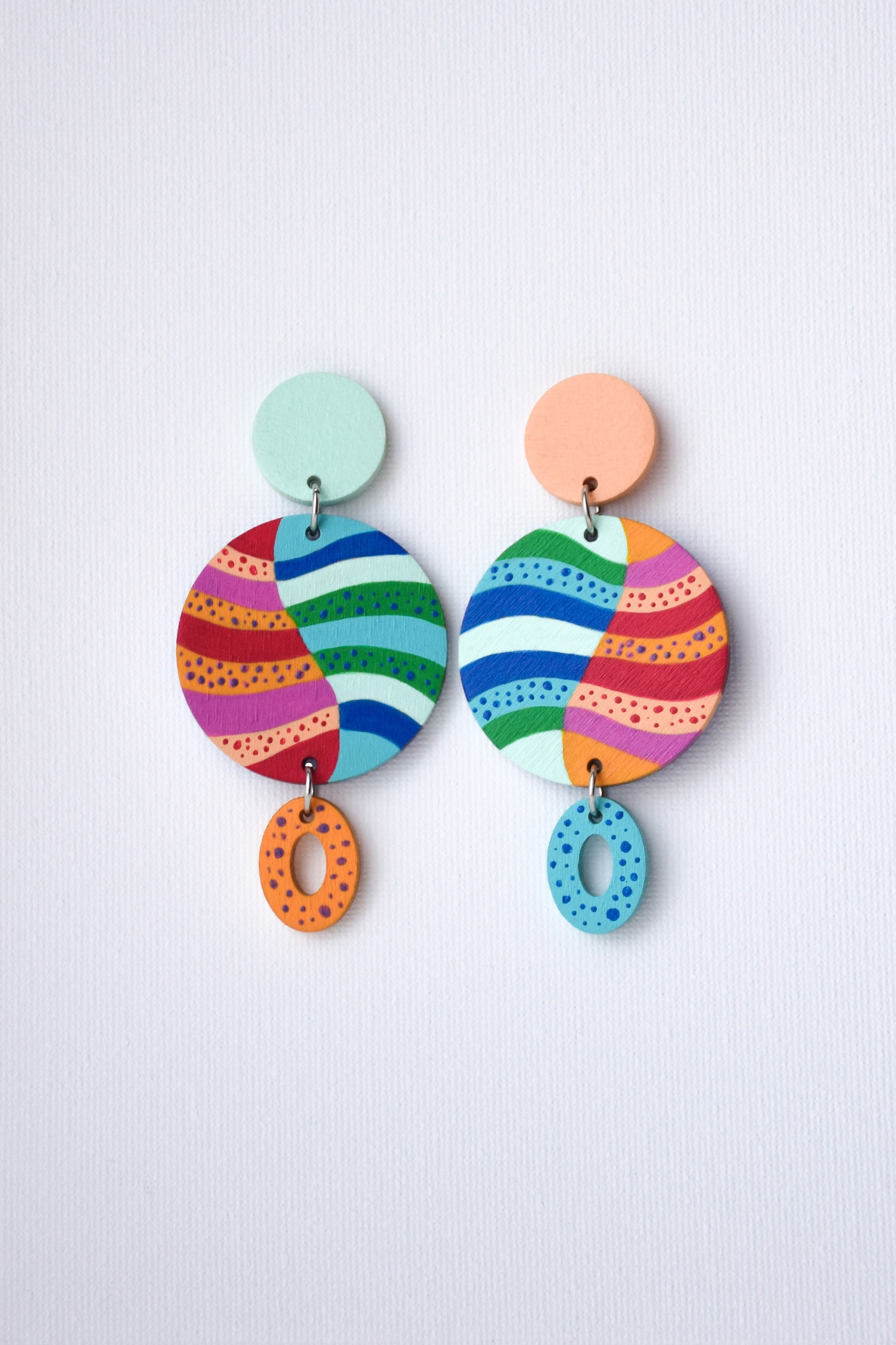 Colorful hand-painted earrings with striped patterns on a light gray background