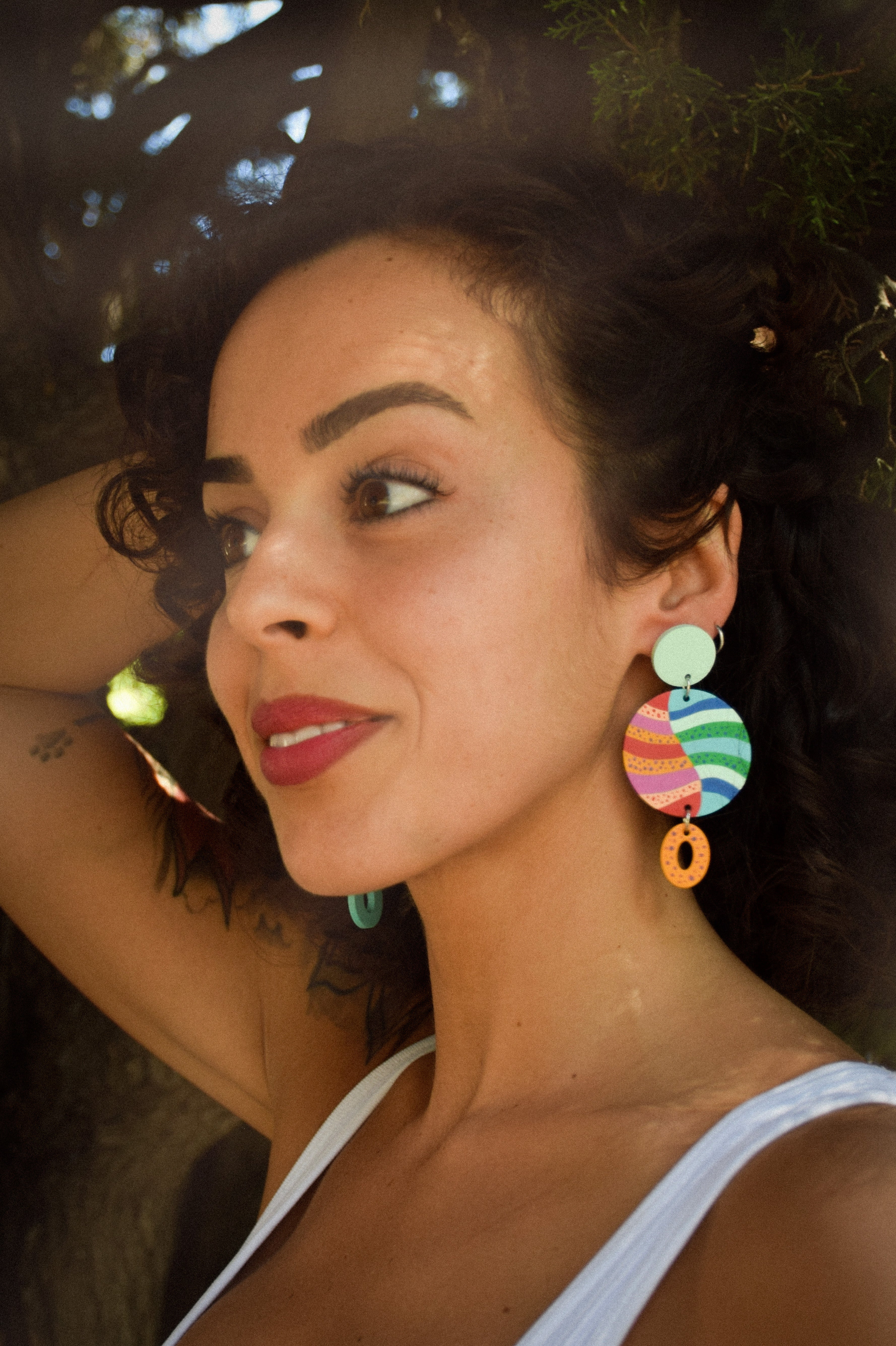 Woman wearing colorful earrings with a blurred natural background