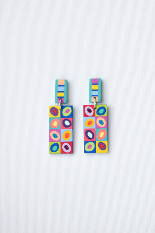 Colorful hand-painted geometric patterned earrings on a light gray background
