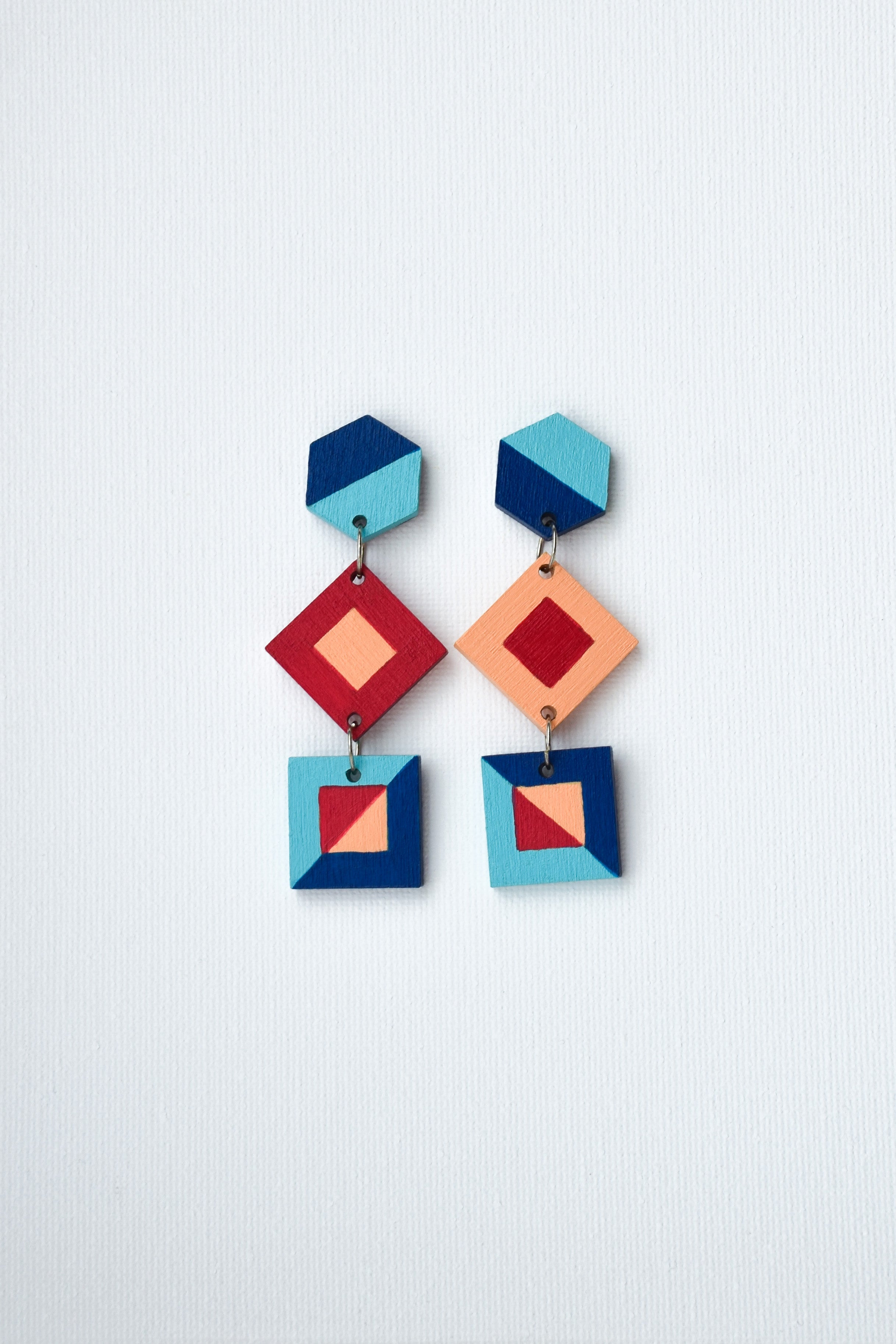 Colorful hand-painted geometric earrings on a light gray background