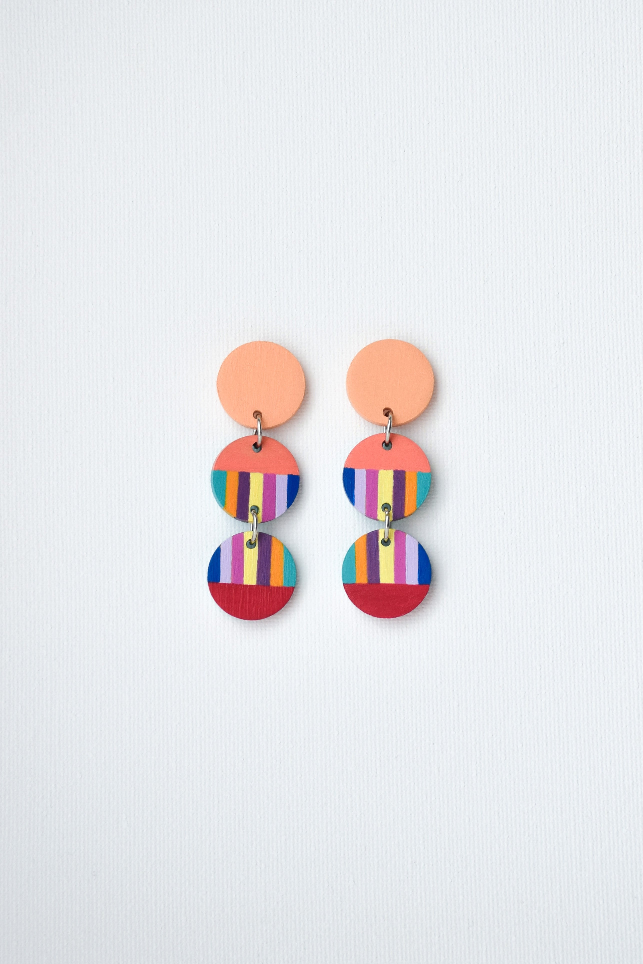 Colorful hand-painted earrings with multiple circular components on a light gray background
