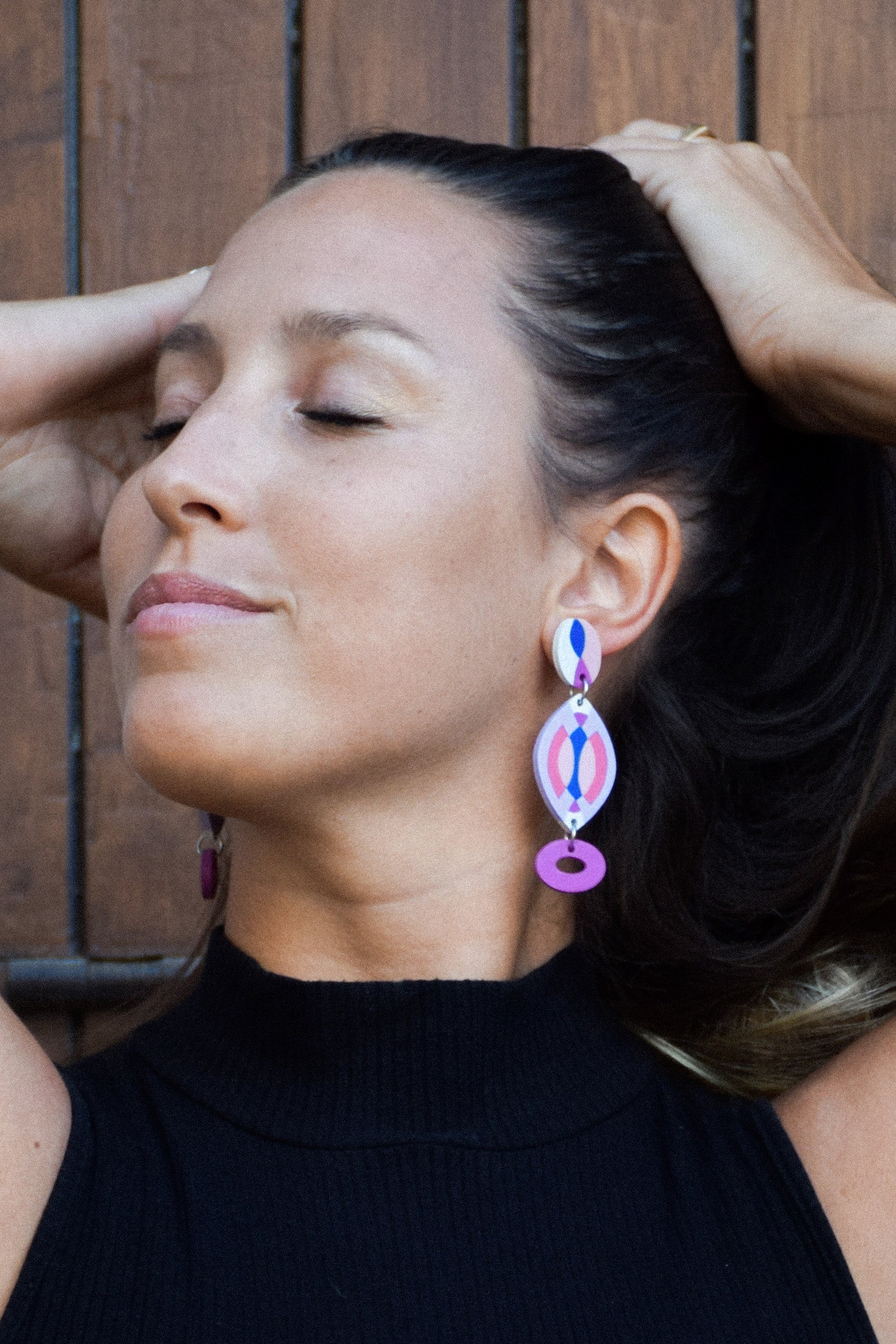Woman wearing colorful earrings with a wooden background