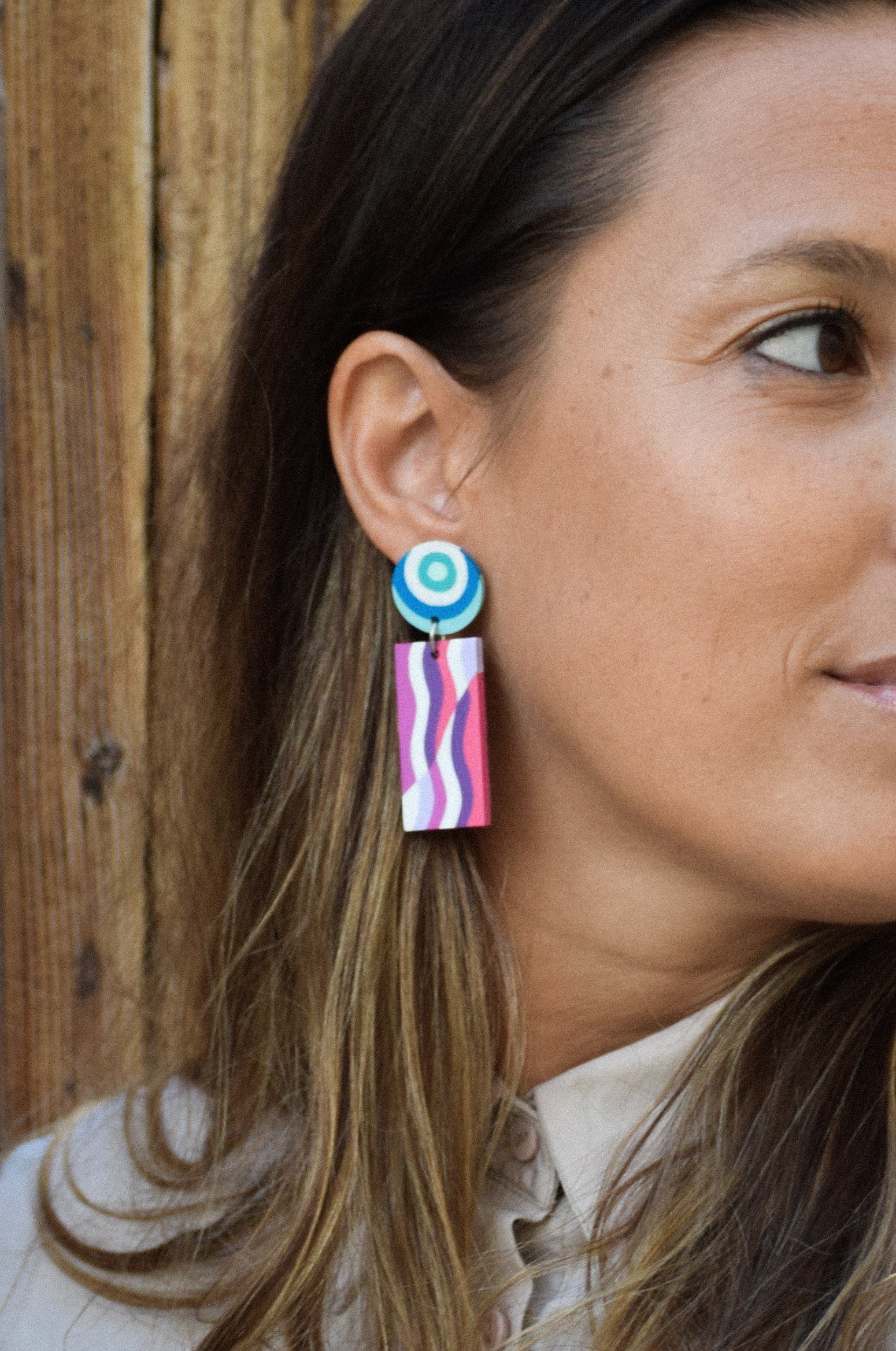 Close-up of a woman wearing colorful earrings with a wooden background