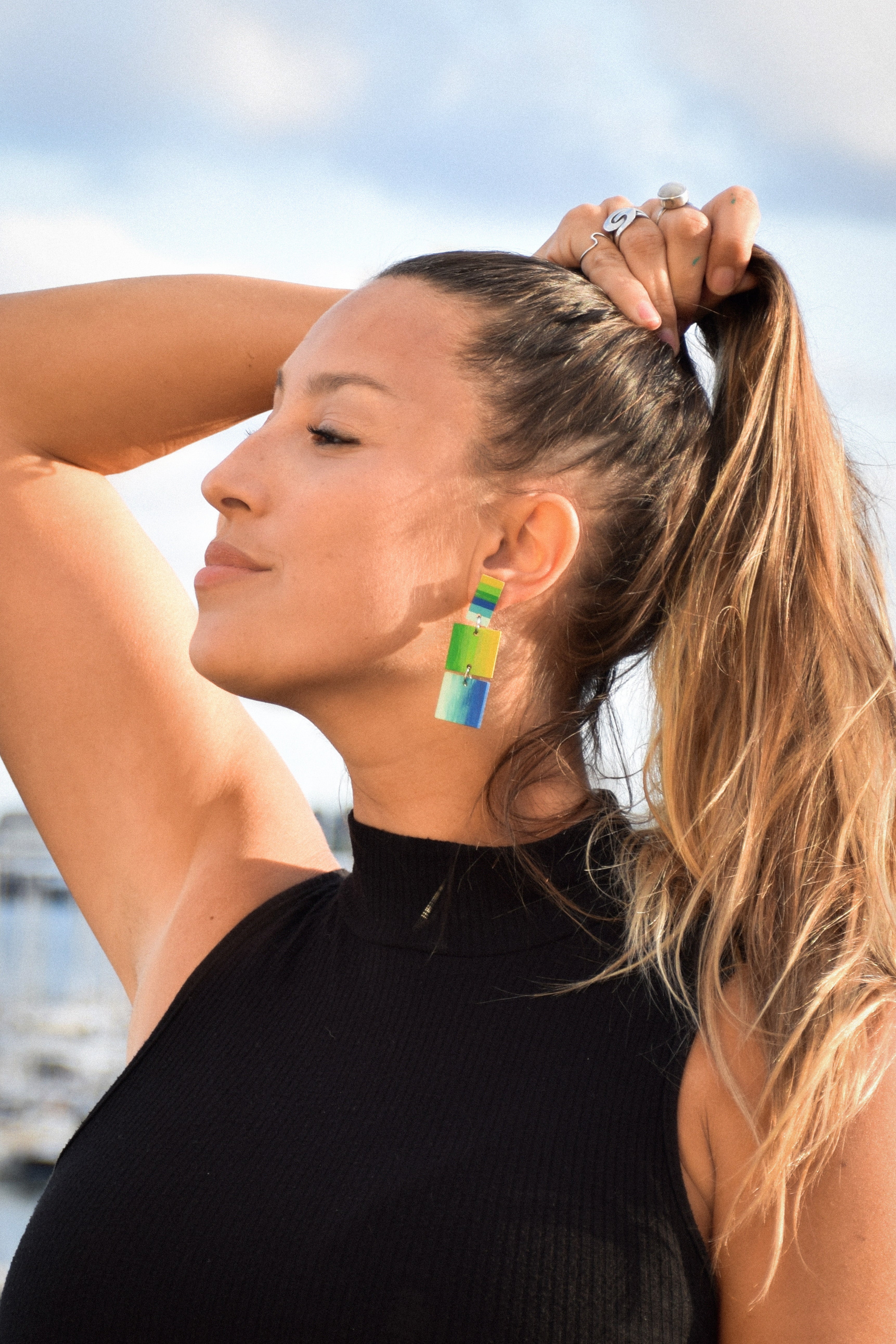 Woman with colorful earrings against a blurred natural background