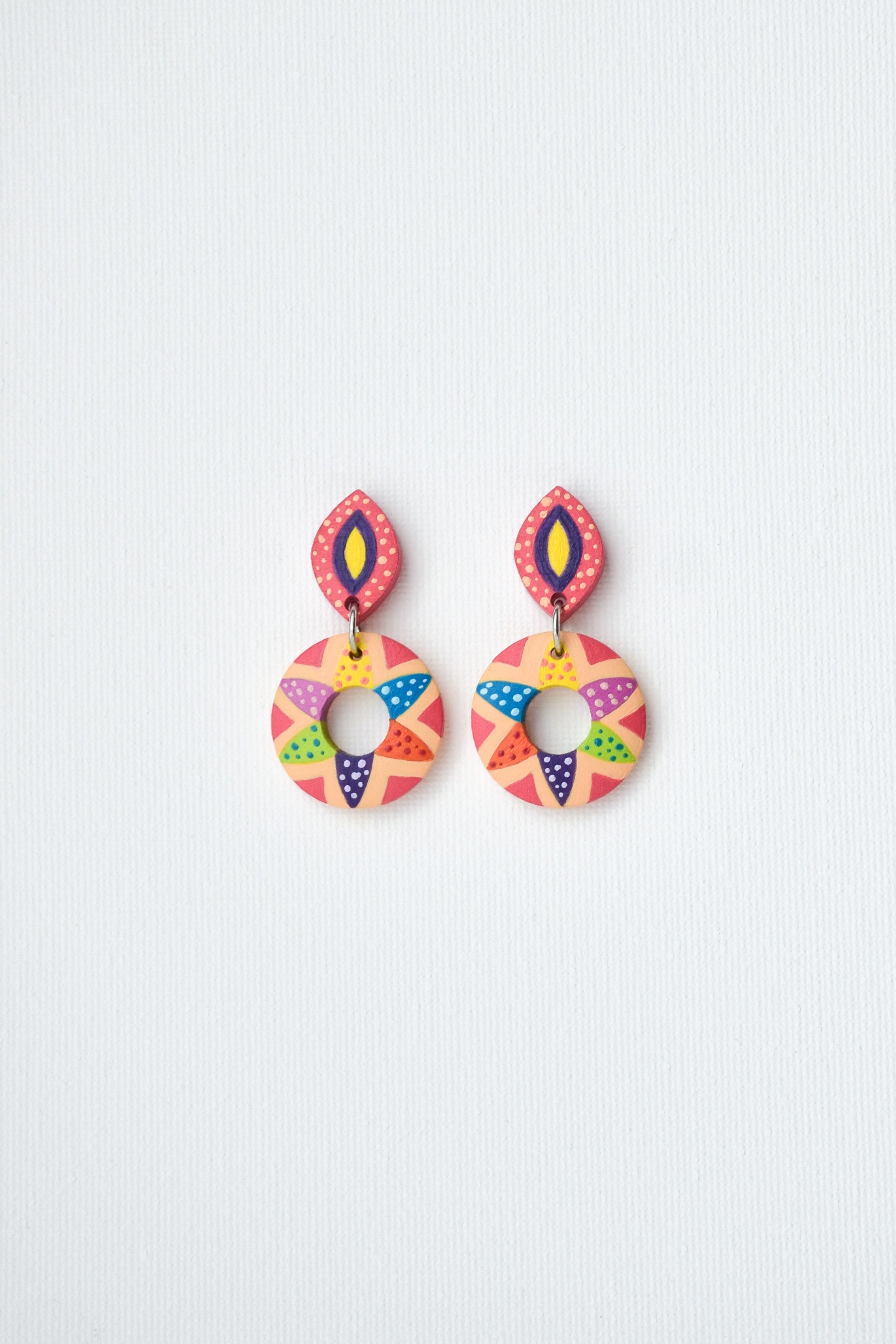 Colorful hand-painted geometric earrings on a light gray background