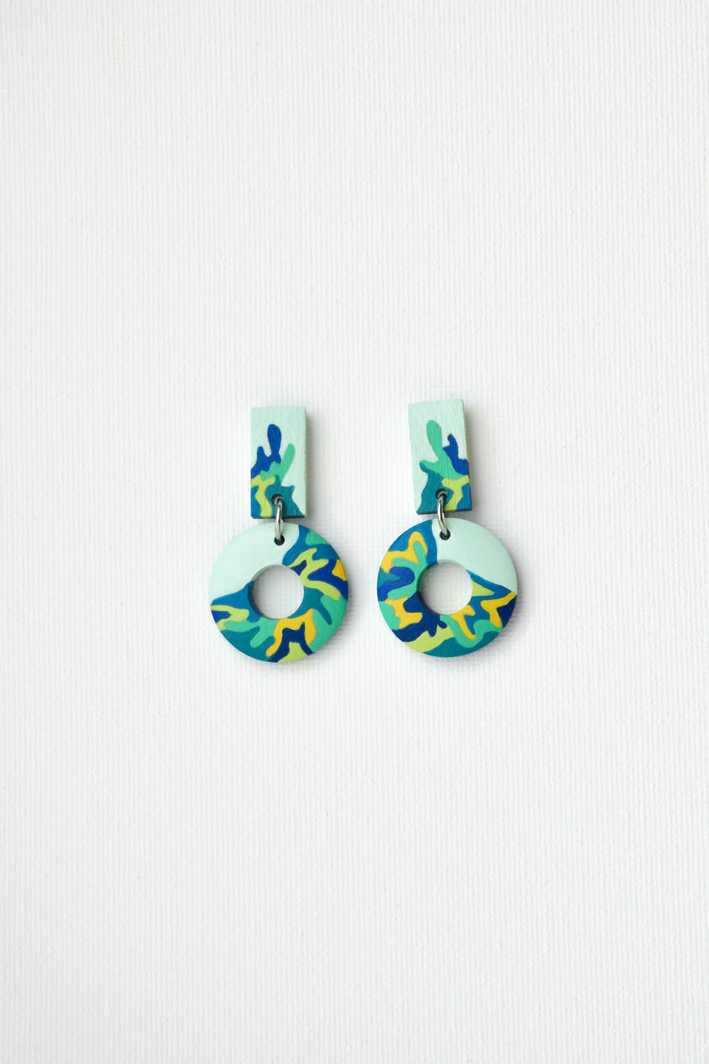 Pair of hand-painted colorful earrings on a light gray background