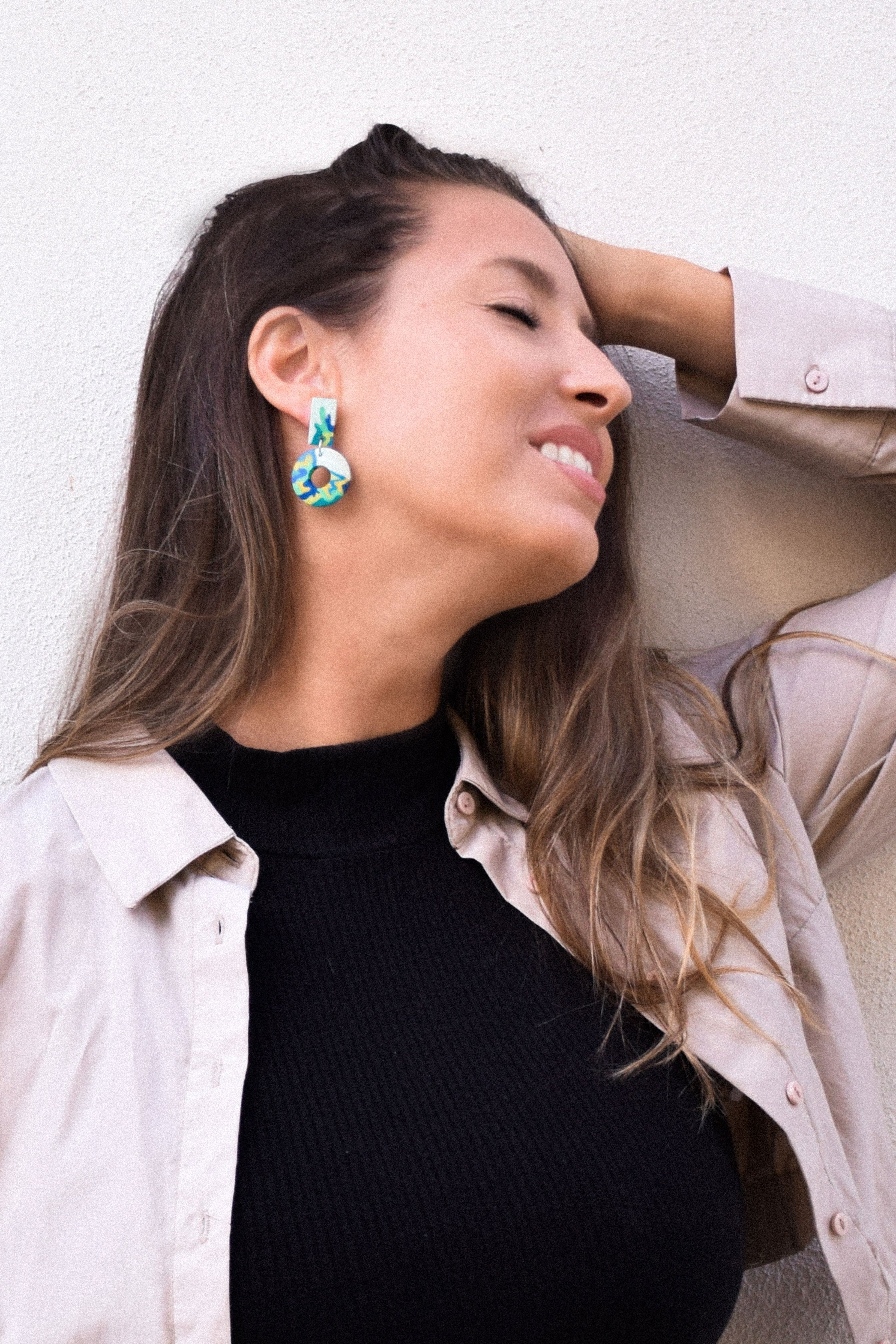 Woman wearing colorful earrings against a light background