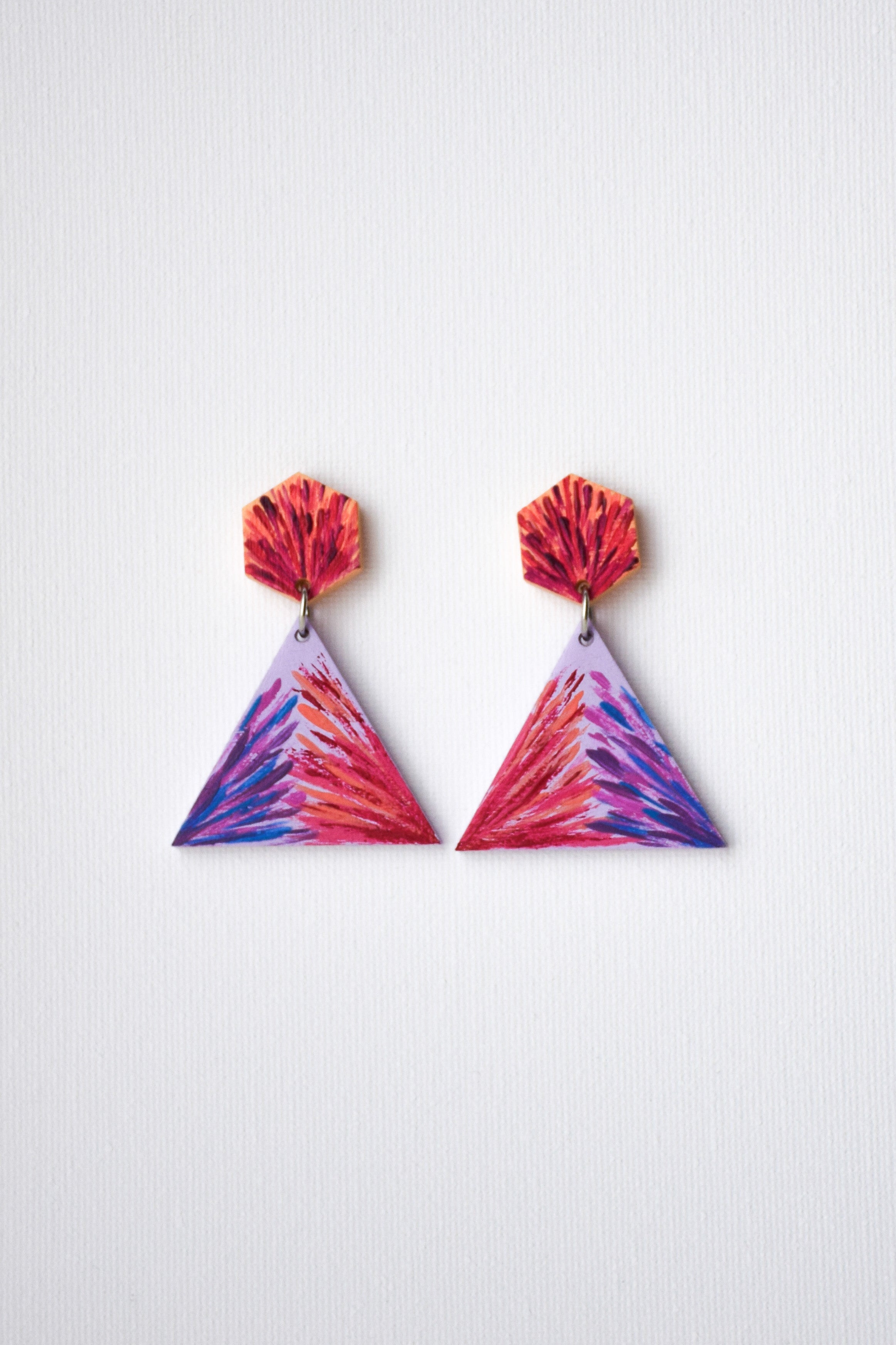 Triangular hand-painted earrings with red and purple design on a white background