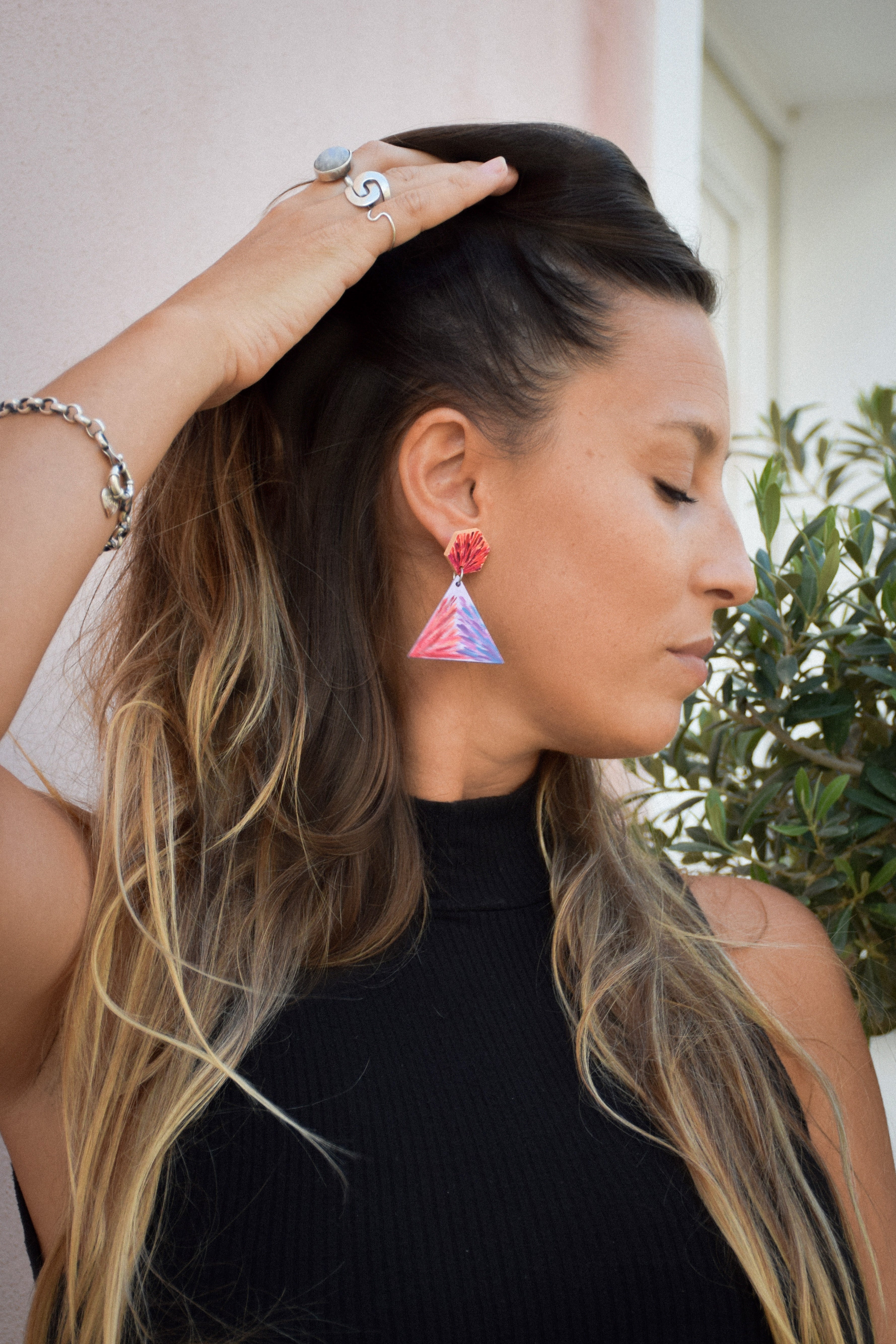 Woman wearing colorful triangle earrings with a blurred background