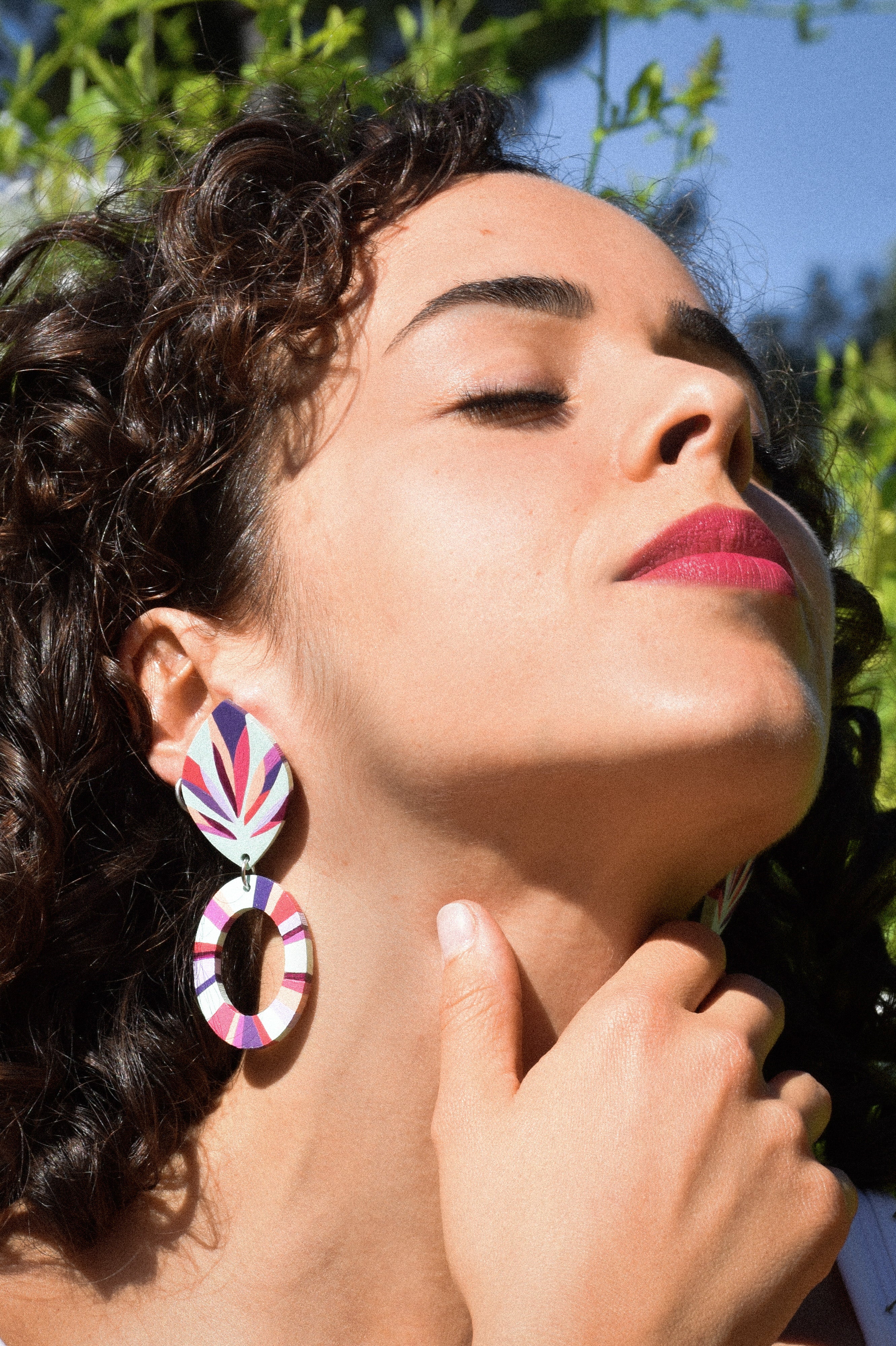 Woman wearing colorful earrings with a blurred natural background