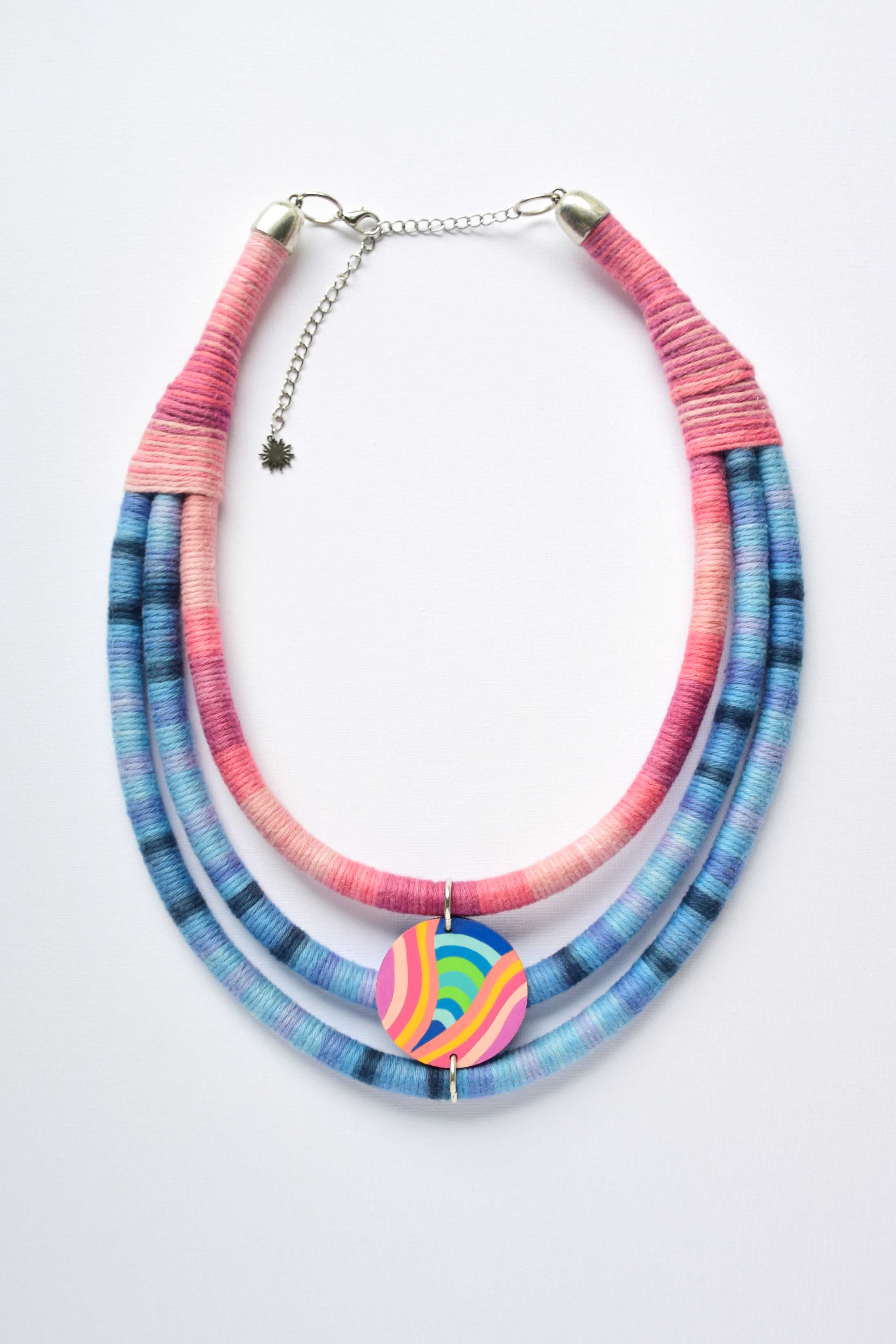 Necklace with pink and blue strands and hand-painted pendant on a white background