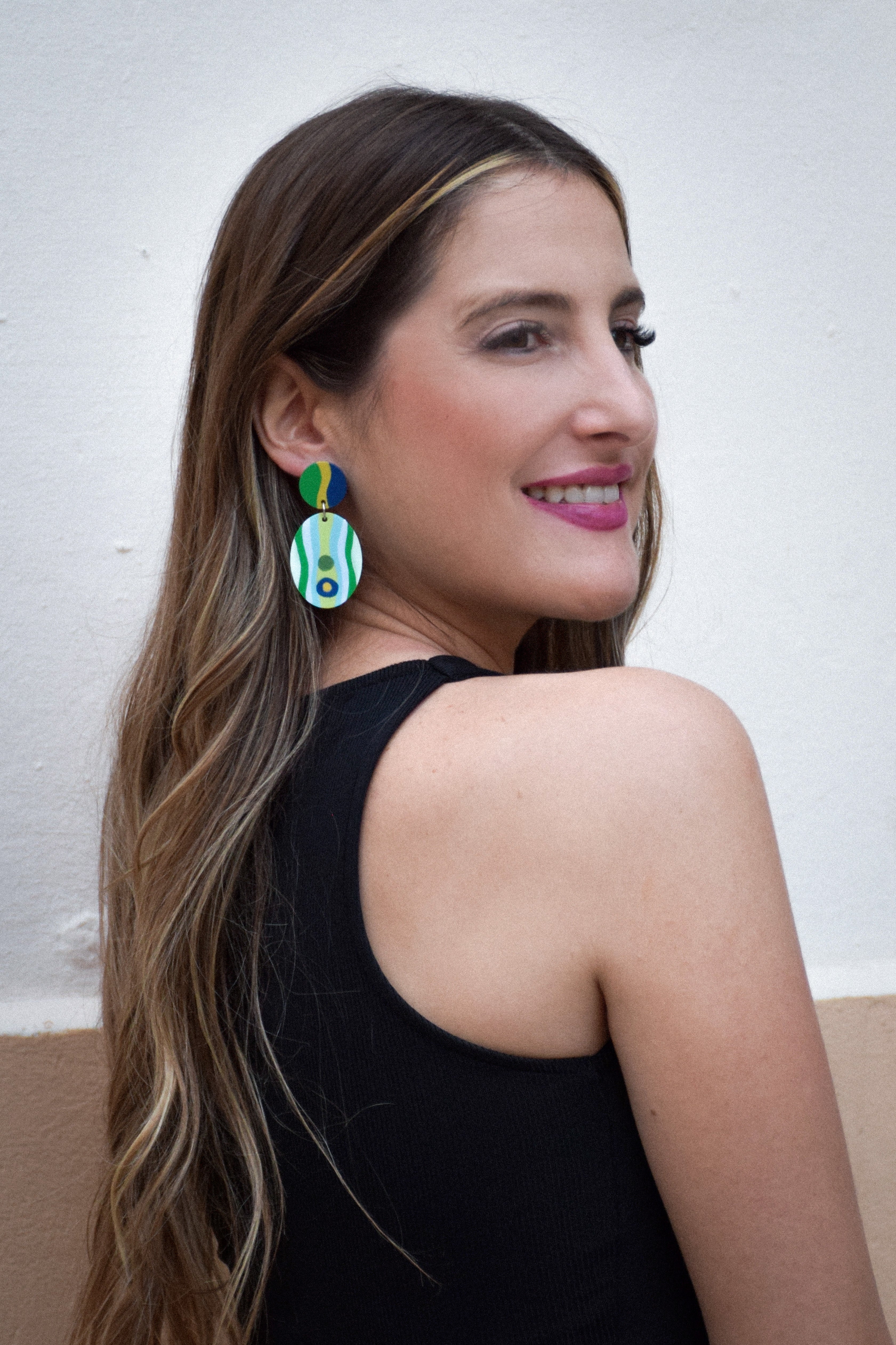 Woman wearing colorful earrings against a plain background