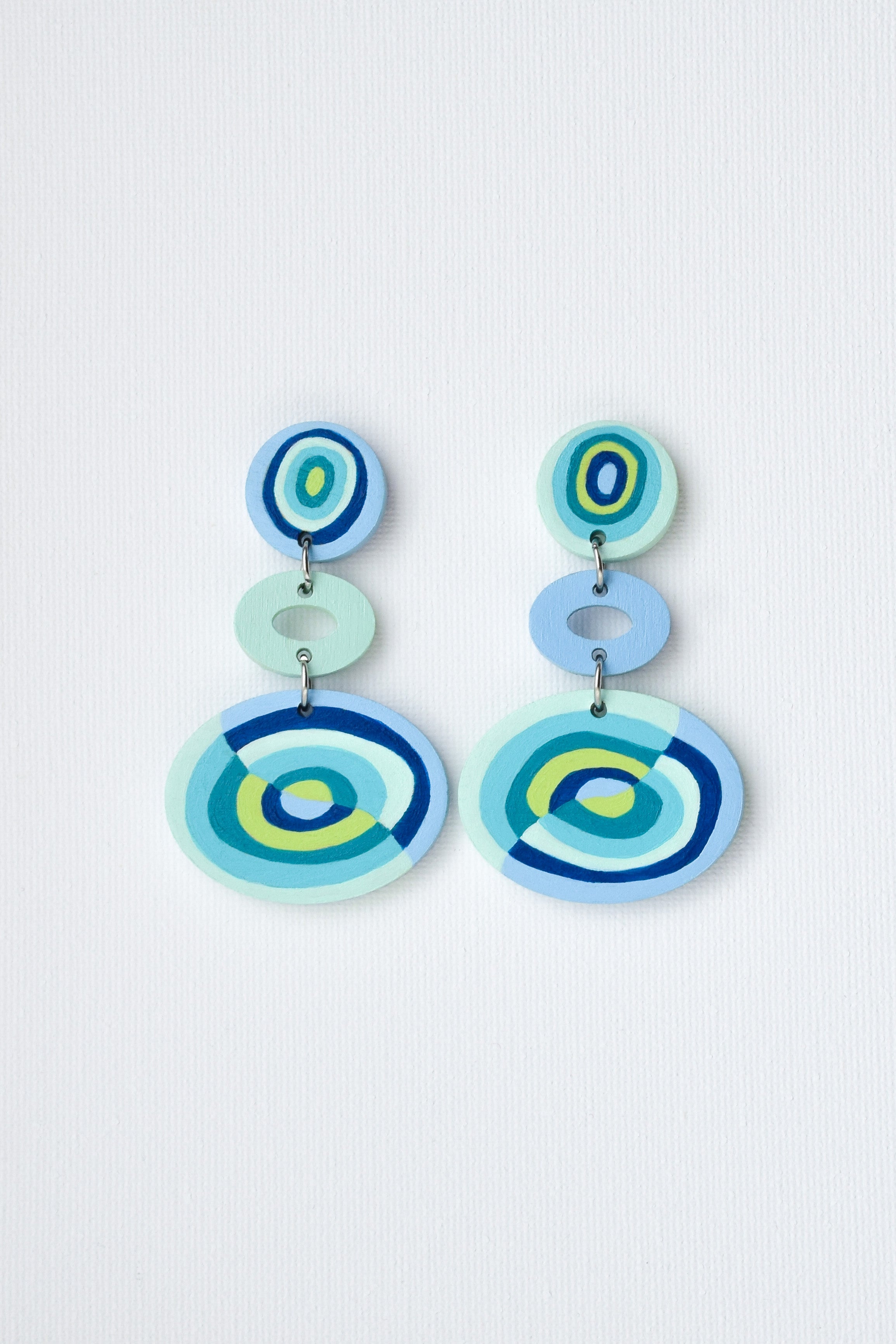 Colorful hand-painted circular earrings on a light blue background