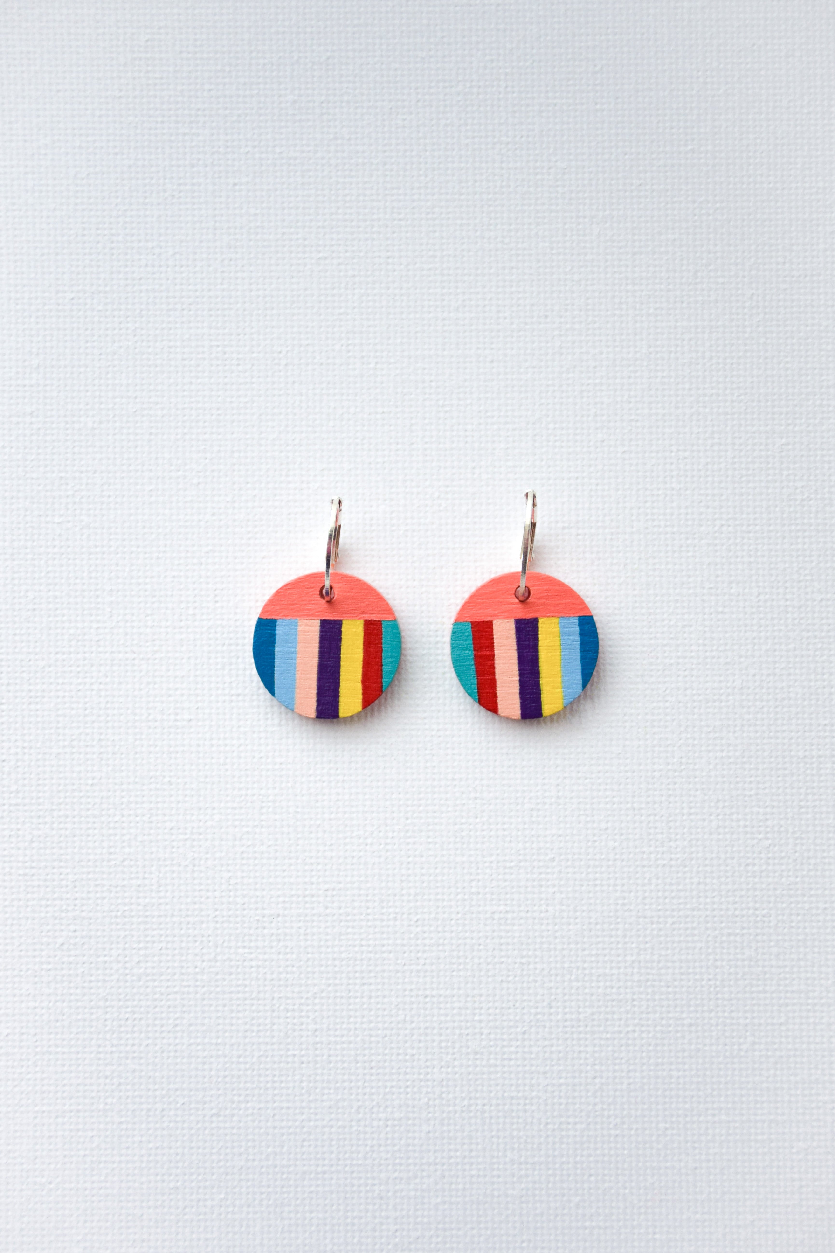 Colorful striped earrings with sterling silver hoops on a light gray background