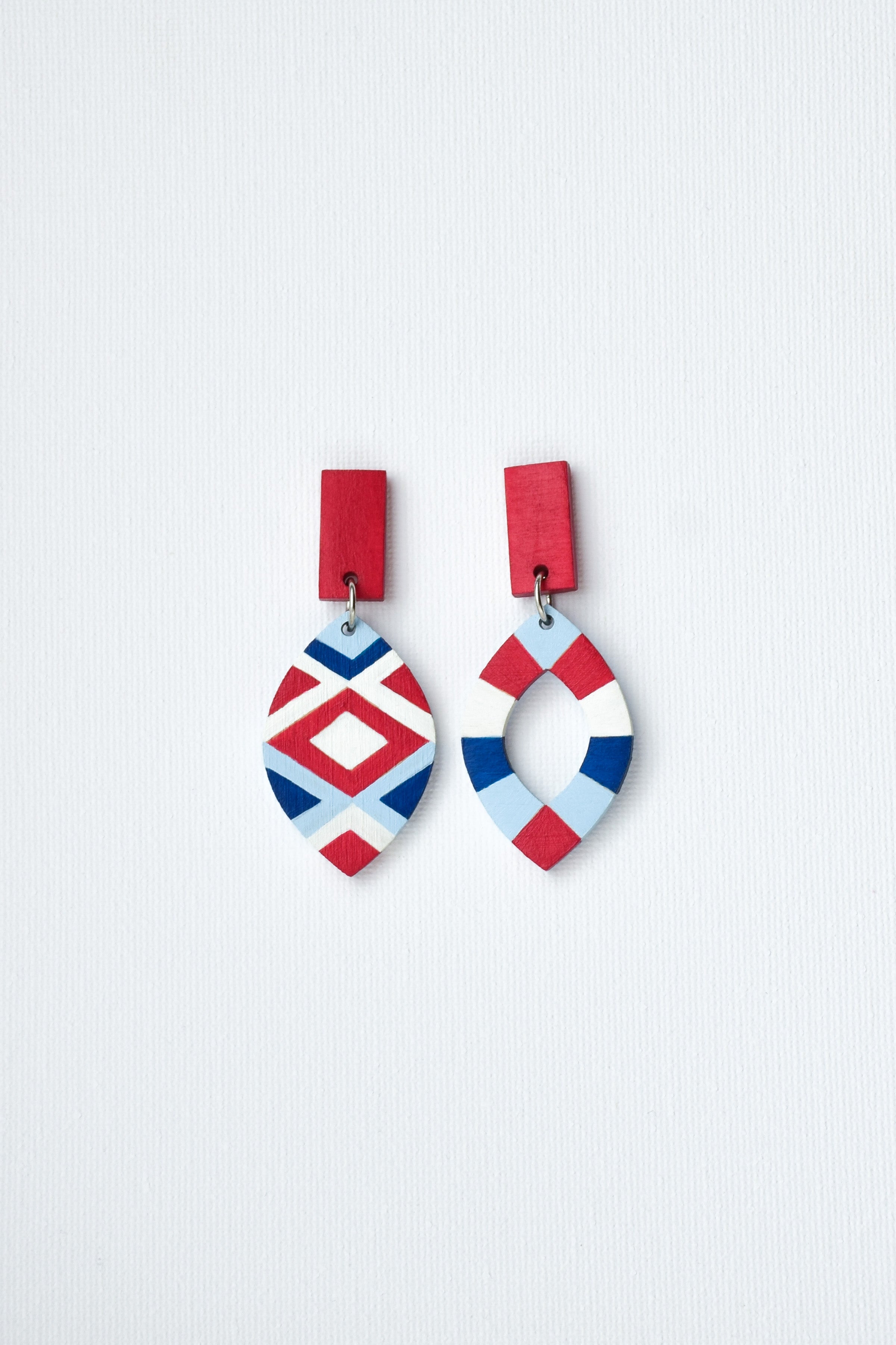 Pair of hand-painted earrings with geometric designs on a light gray background