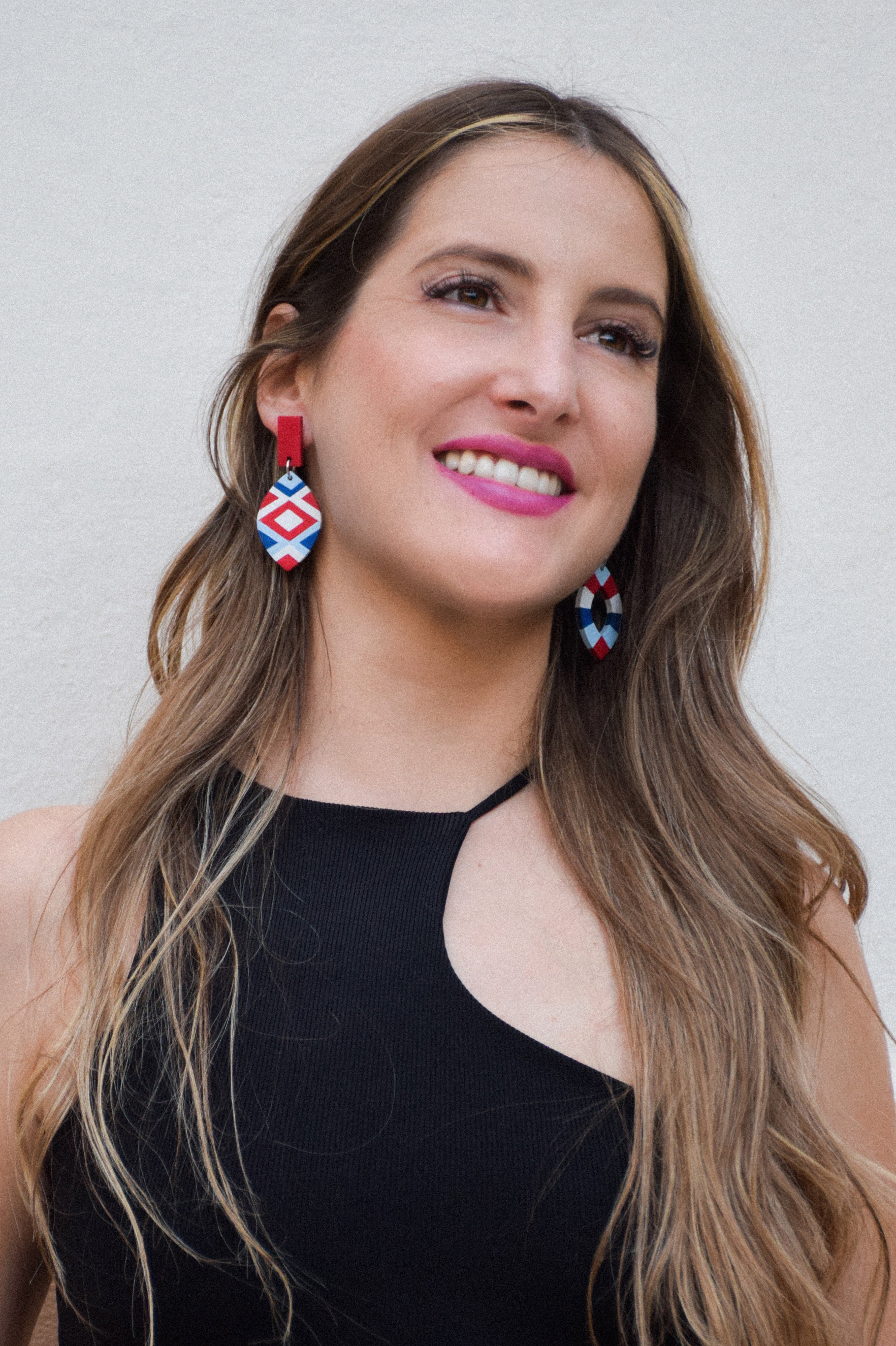 Woman wearing colorful earrings against a plain background