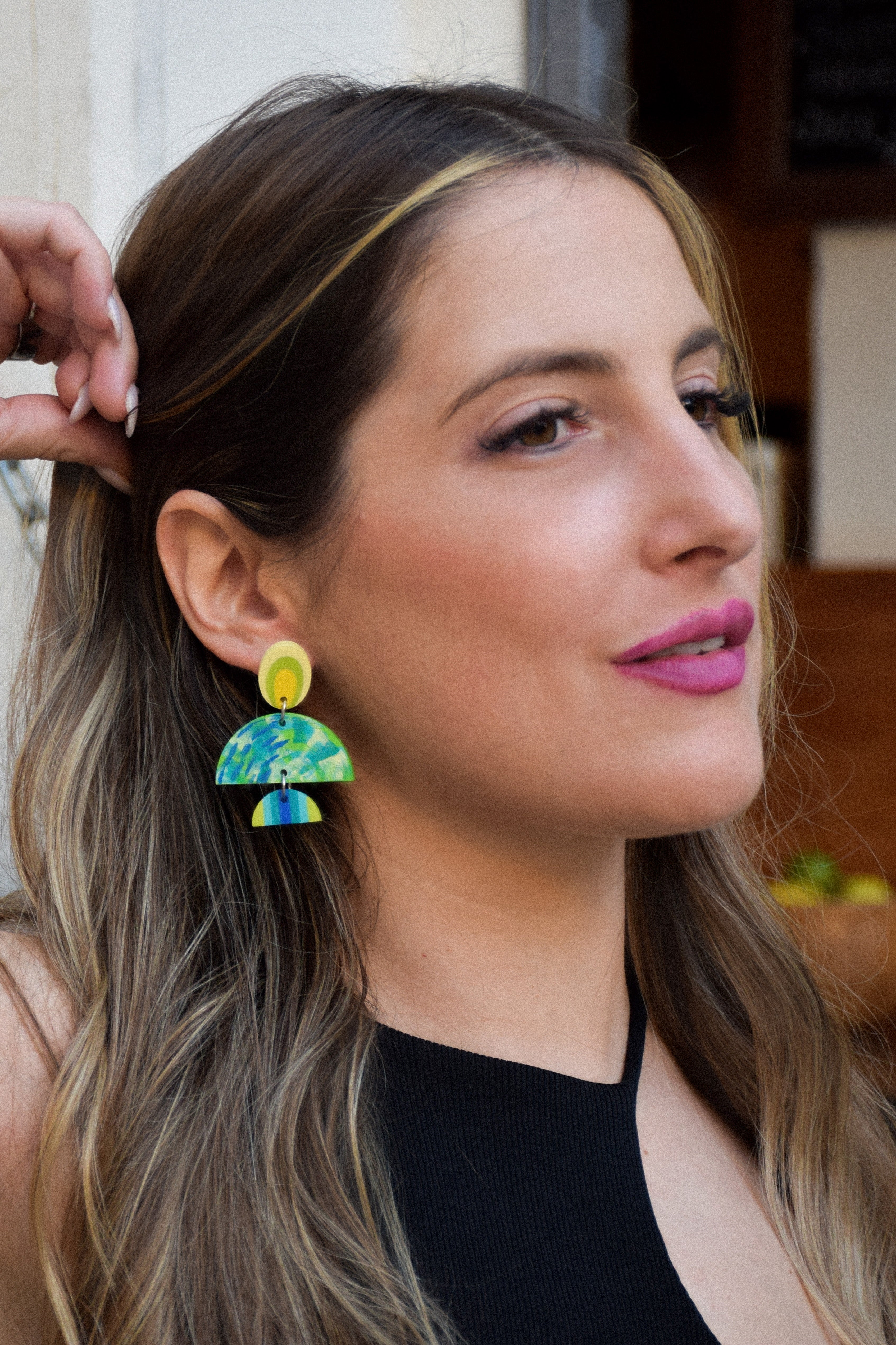Woman wearing colorful earrings with a blurred background