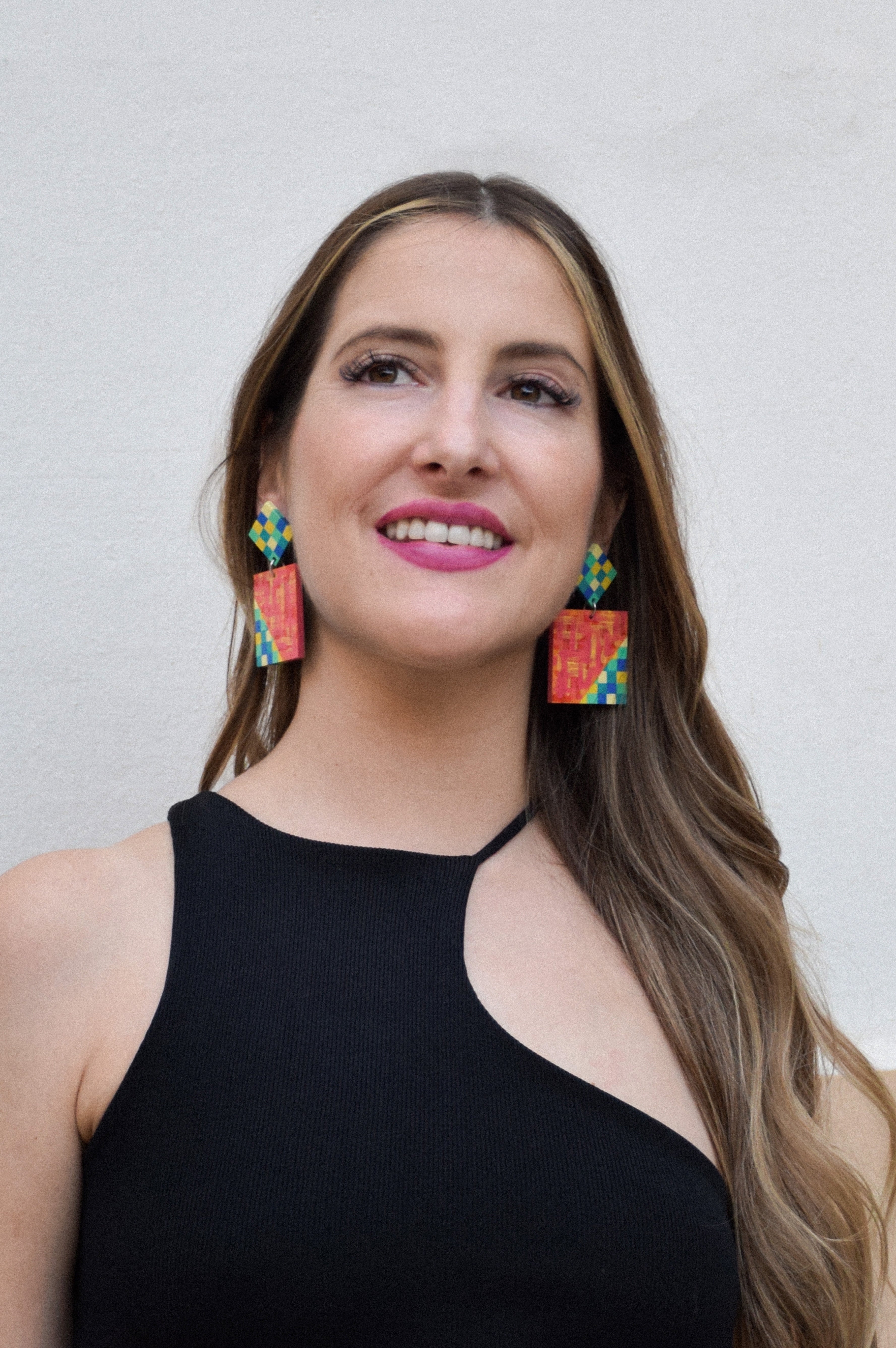 Woman wearing colorful earrings against a plain background