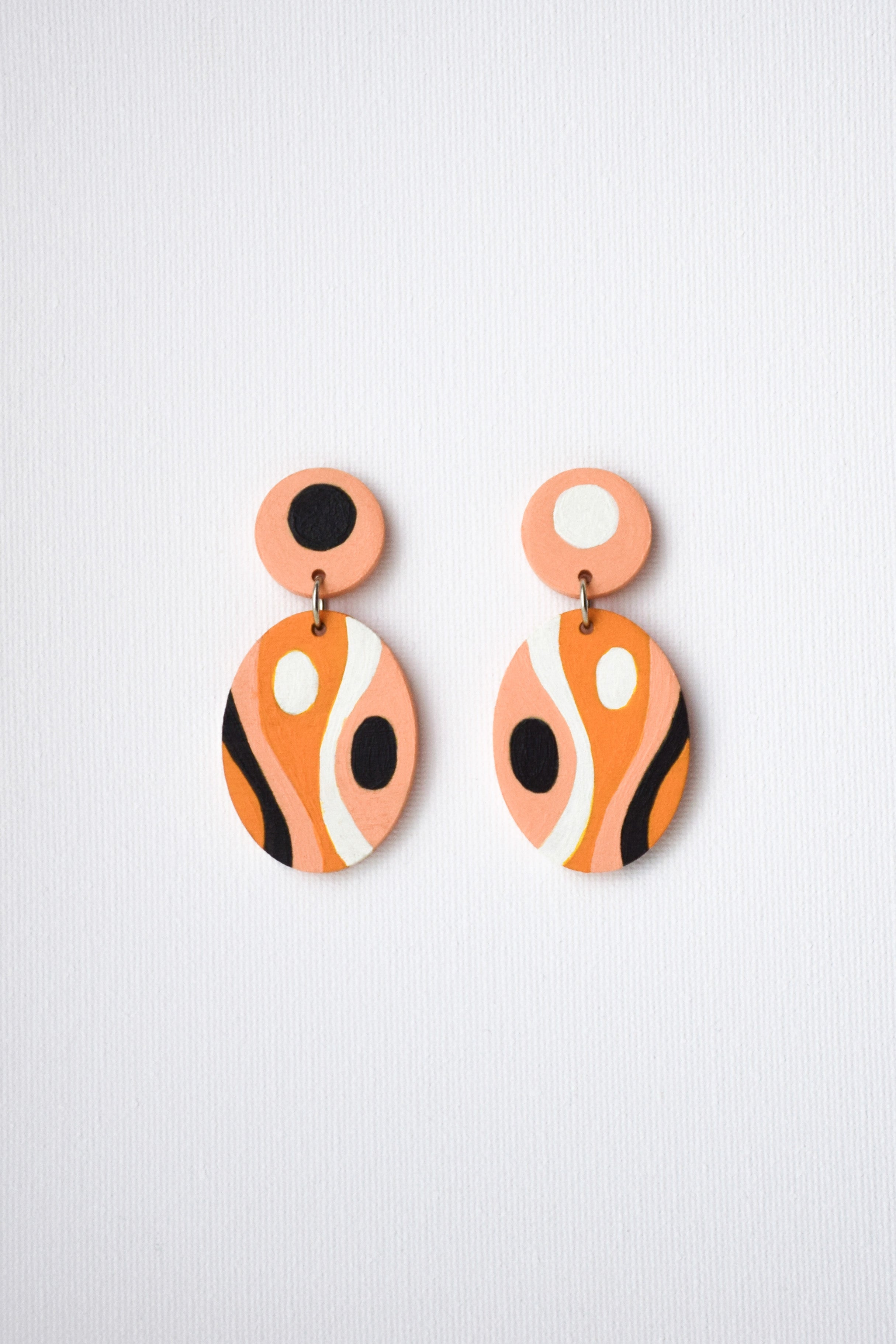 Pair of orange and black earrings on a light gray background