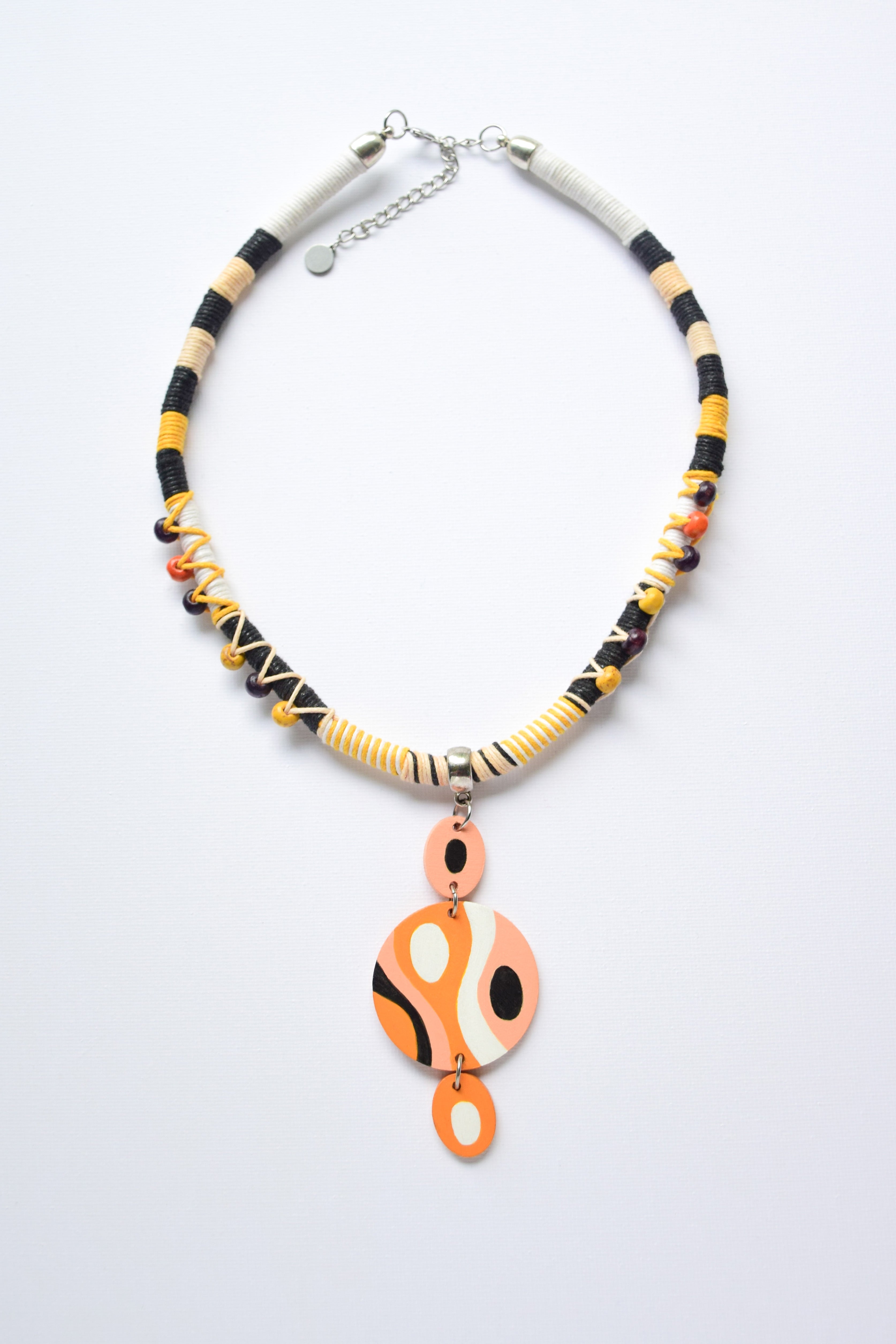 Necklace with black, orange, and white beads and hand-painted pendant on a white background