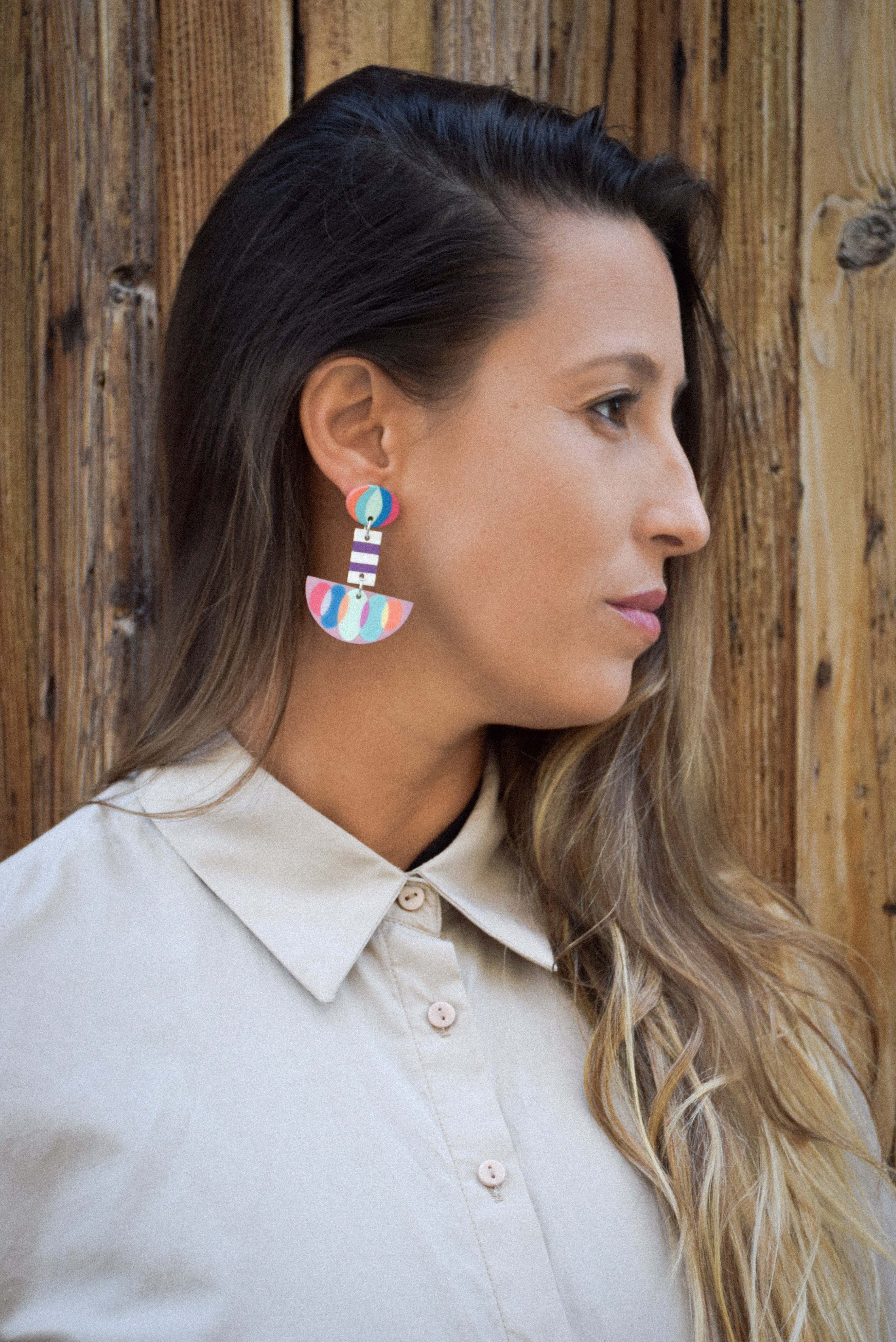 Woman wearing colorful earrings against a wooden background