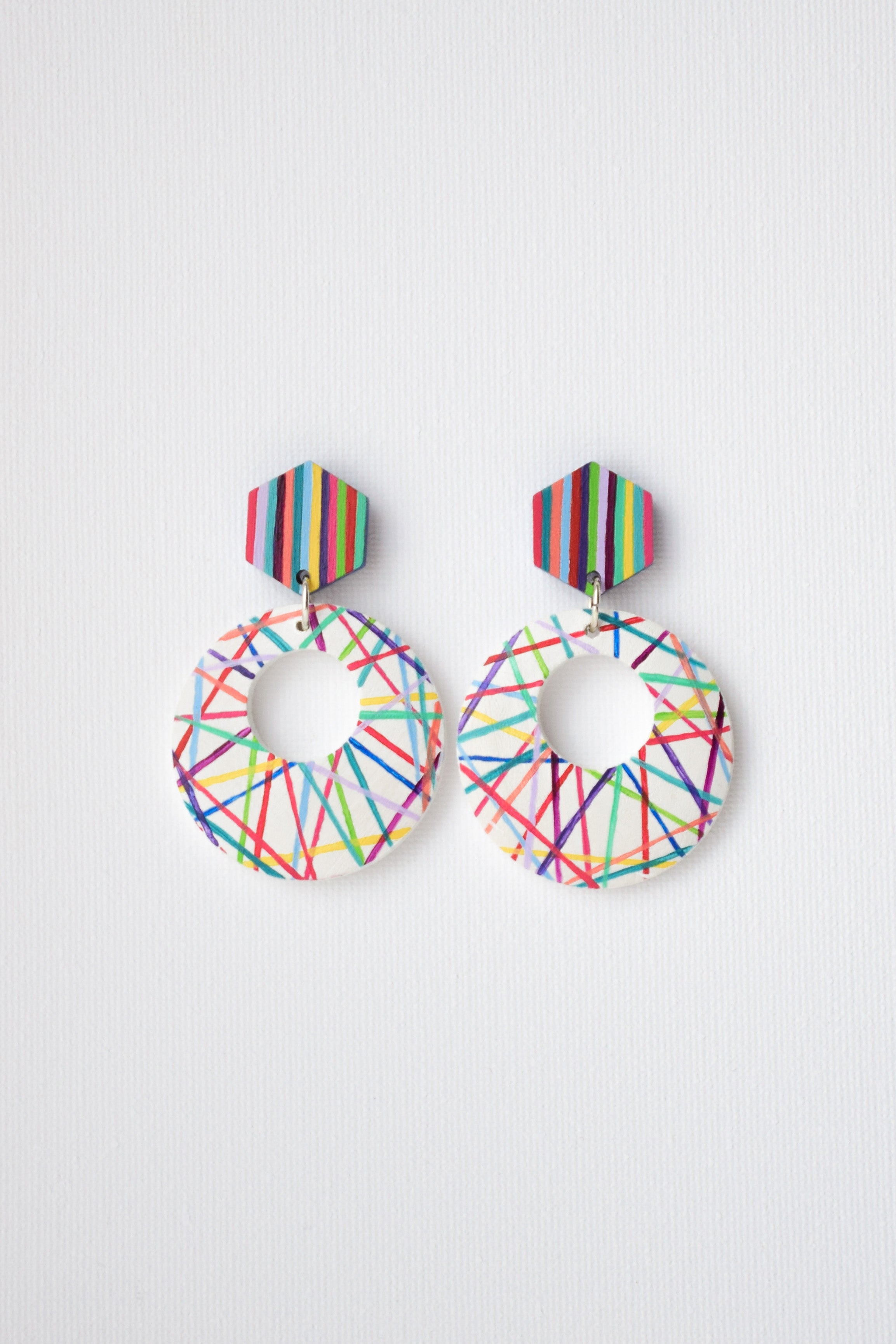 Colorful geometric hoop earrings on a white background