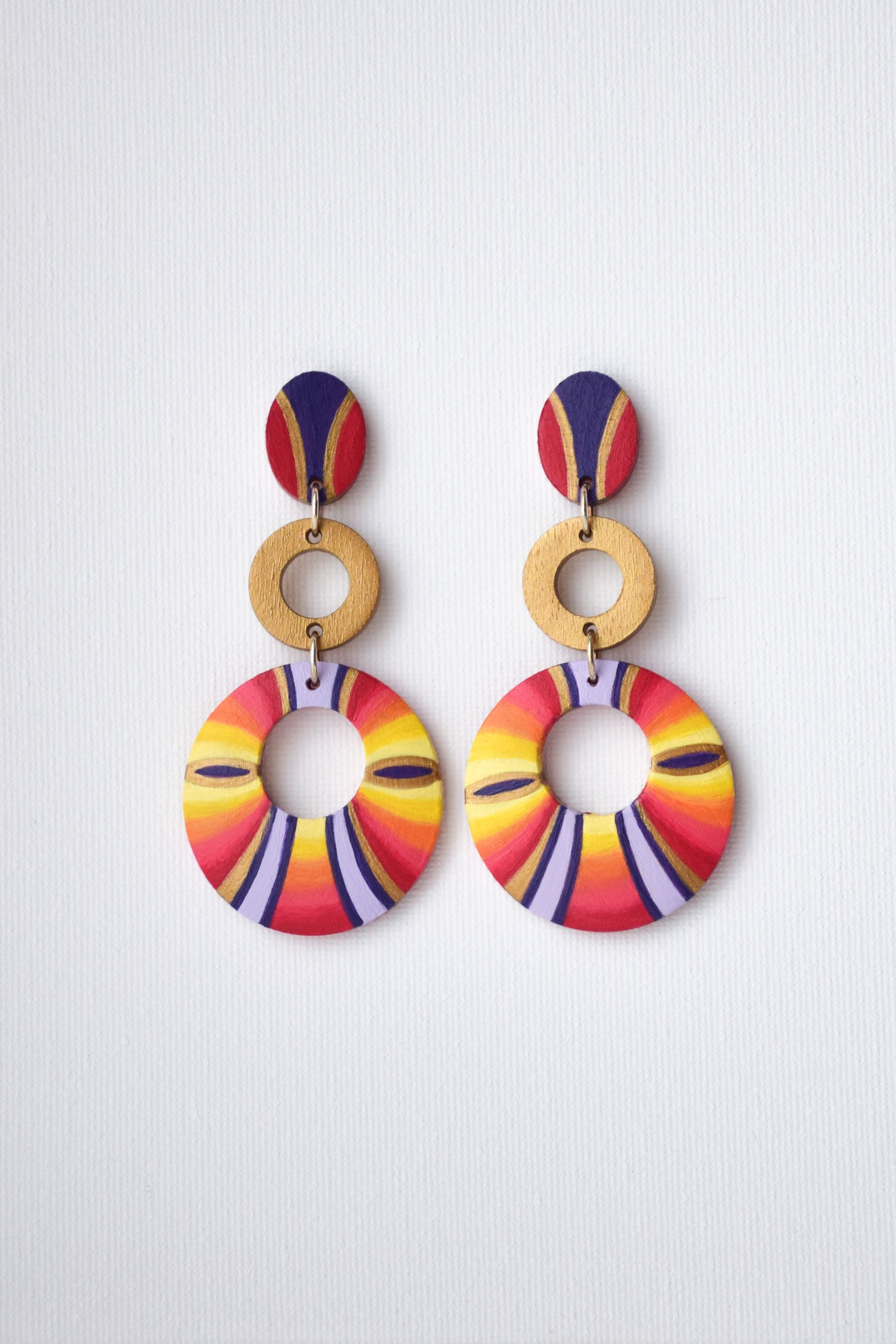 Colorful hand-painted circular earrings on a light gray background