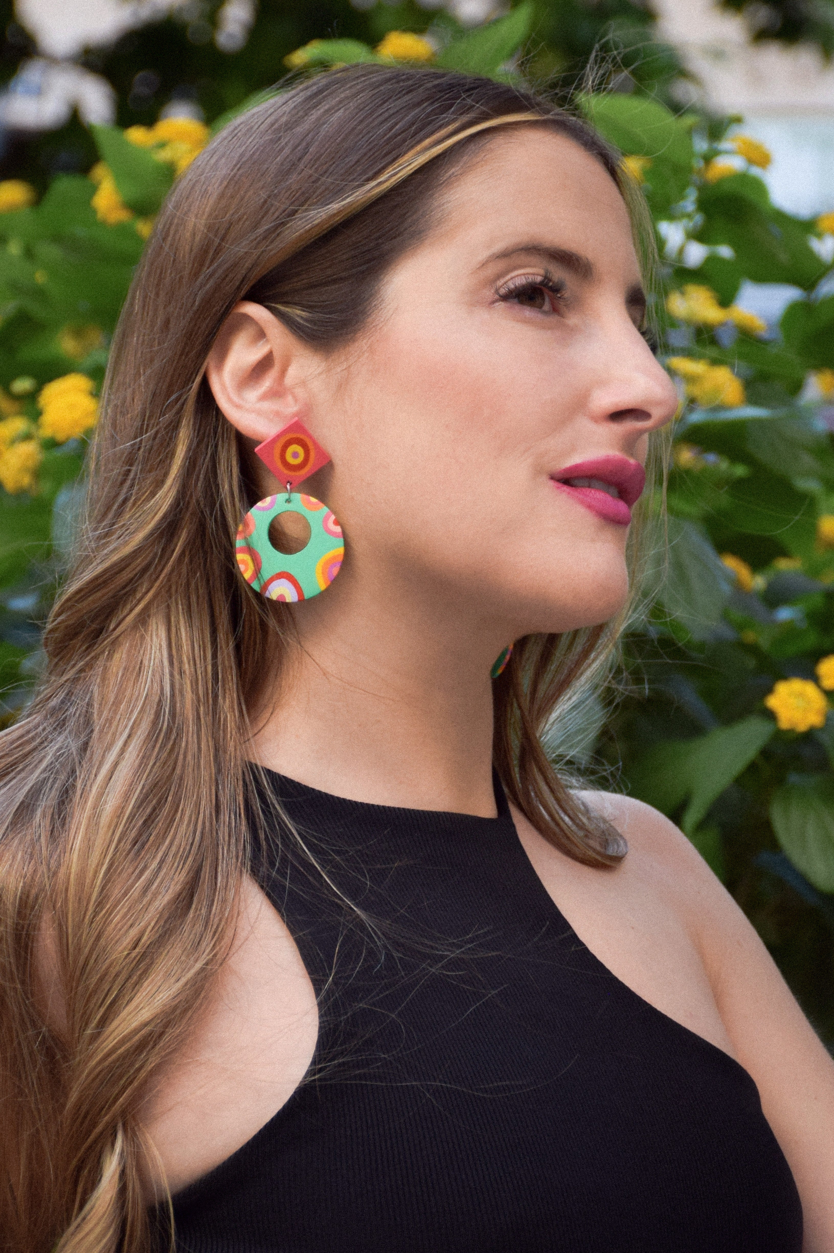 Woman wearing colorful earrings with a floral background
