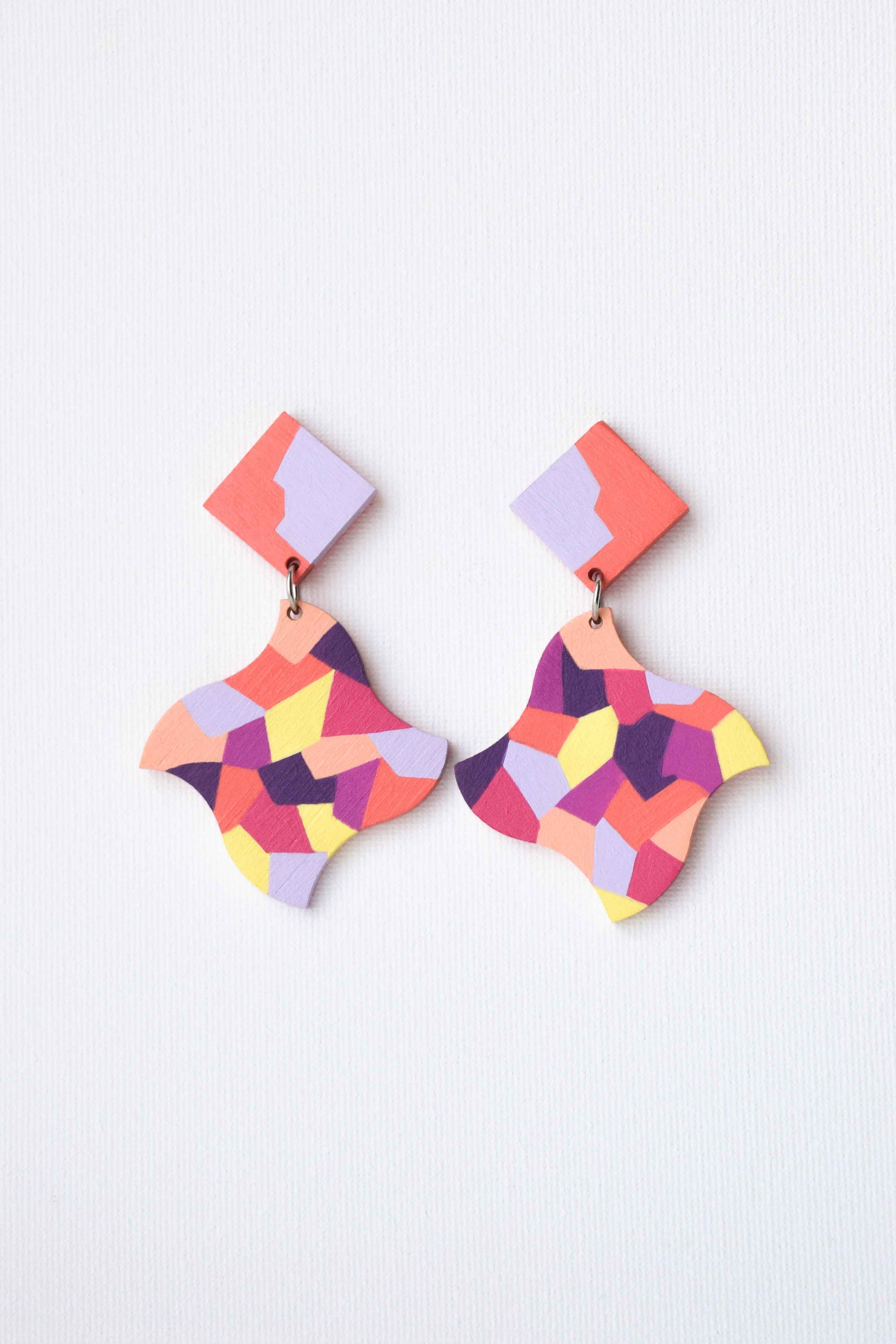 Colorful hand-painted geometric earrings on a light gray background