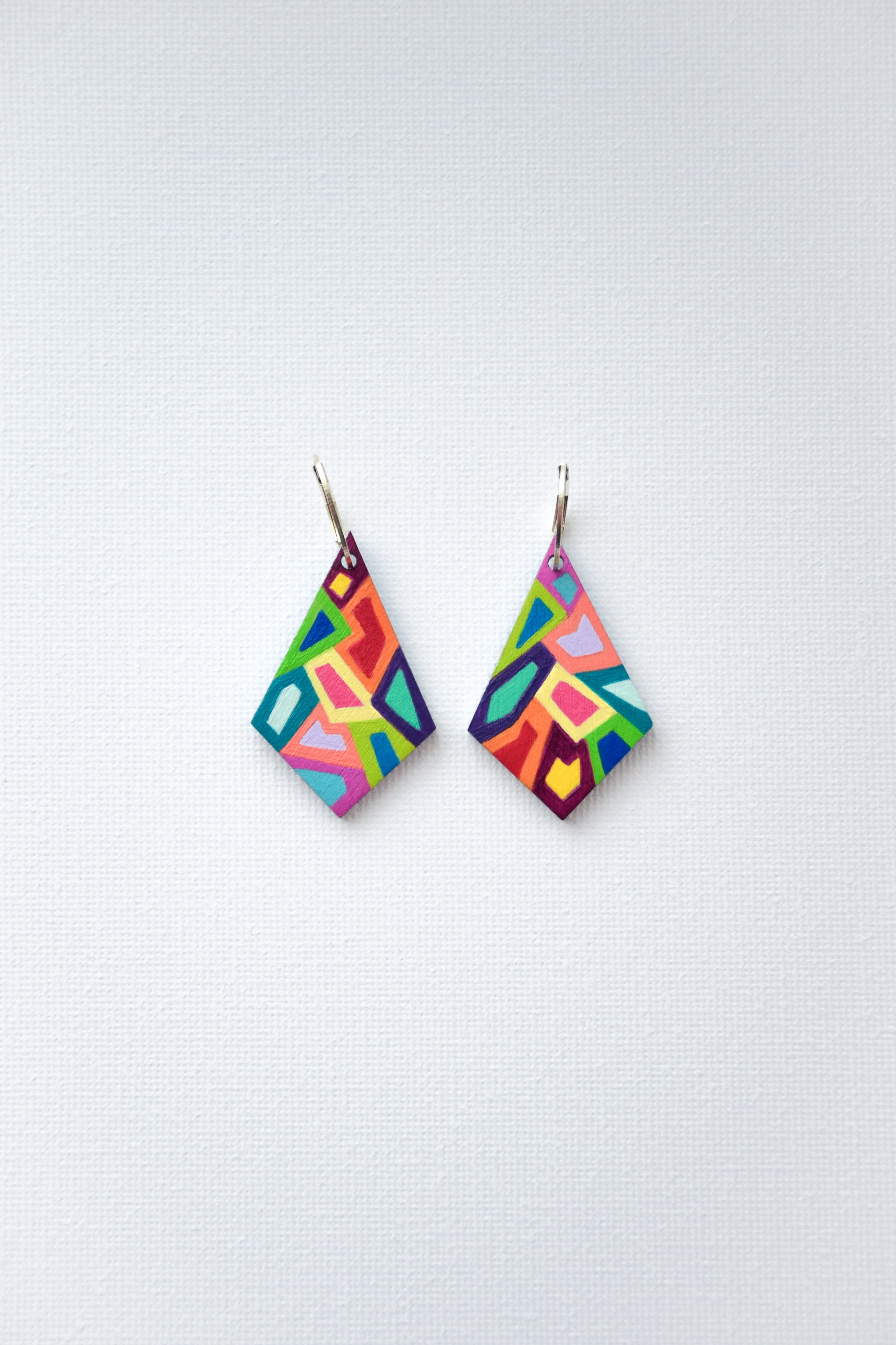 Colorful geometric earrings with sterling silver hoops on a white background