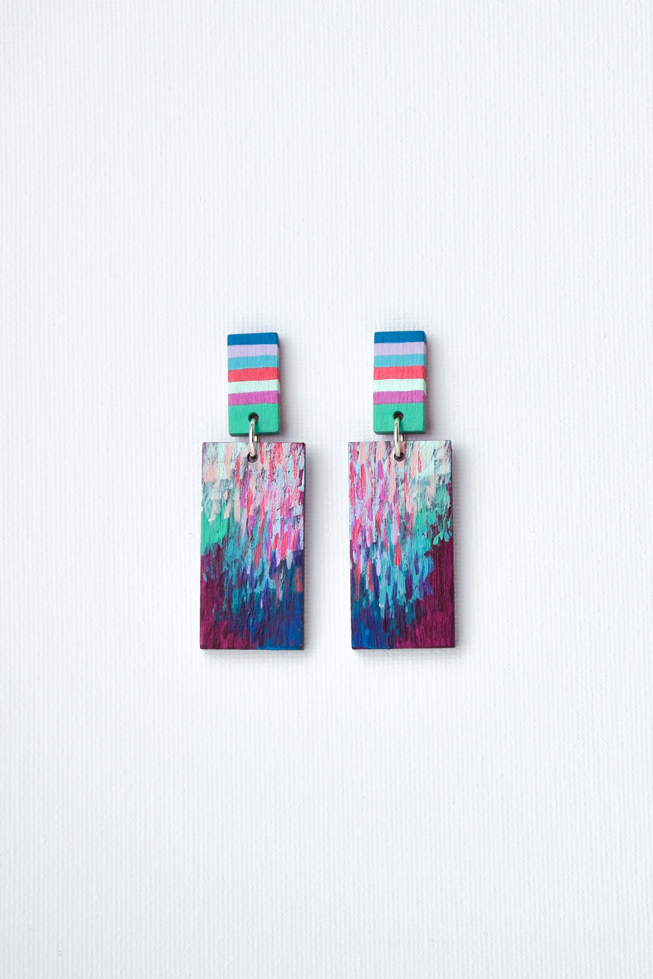 Pair of hand-painted colorful earrings with striped tops on a white background