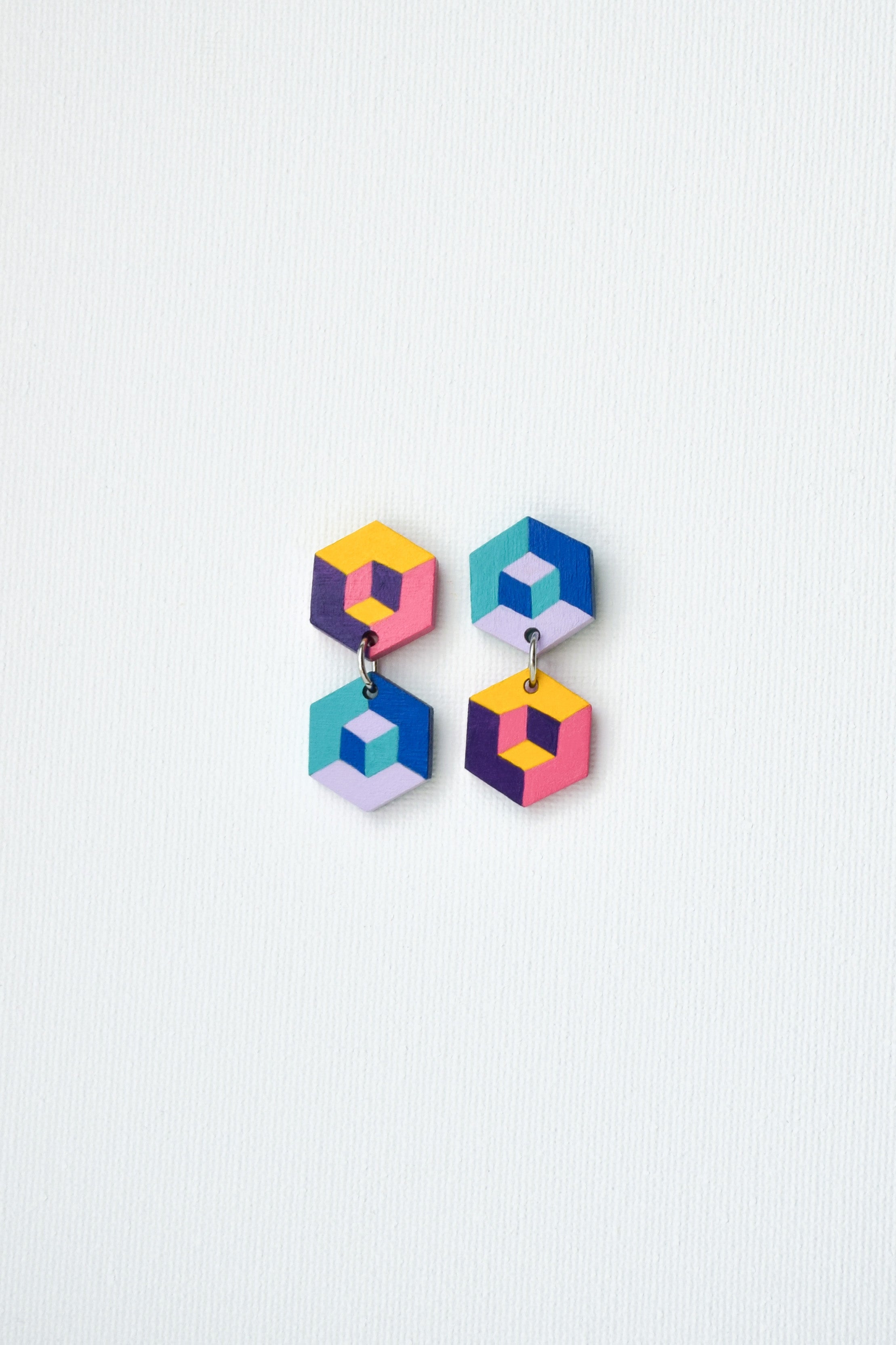 Colorful hand-painted geometric earrings on a light gray background